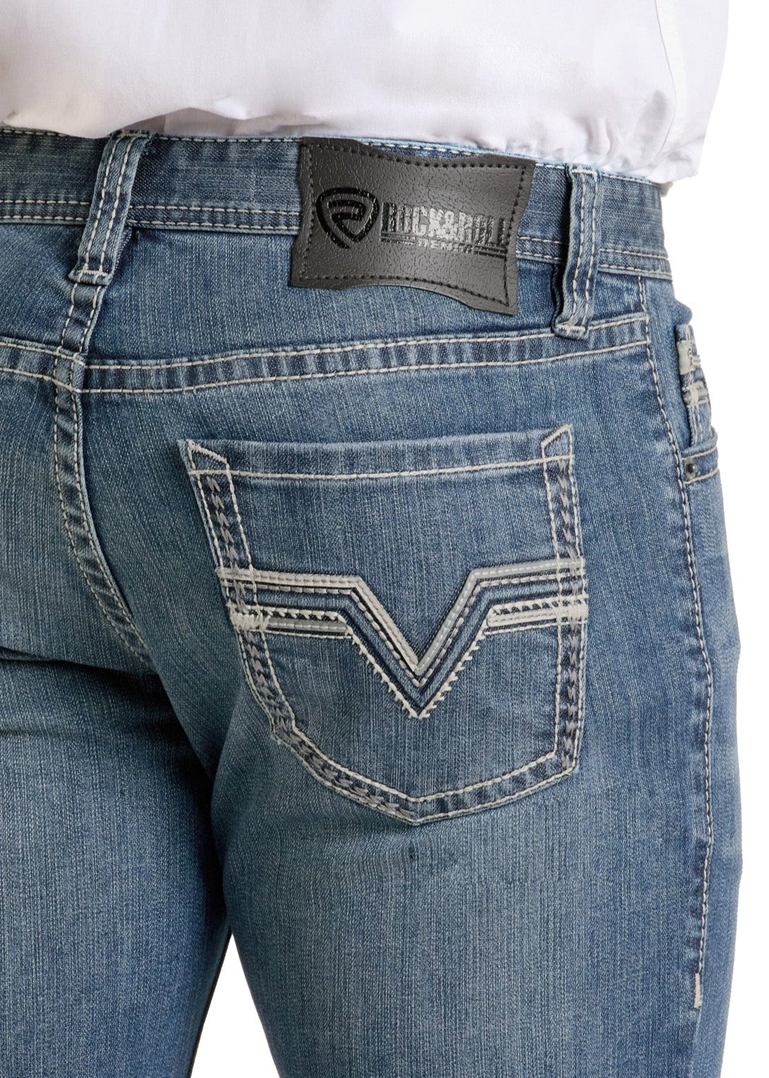 A person is seen from the back wearing Rock & Roll Denim’s Slim Fit Embroidered Pleather Straight Leg Jeans in medium wash, with white stitching, a black leather waistband patch, and V-shaped embroidery on the back pockets.