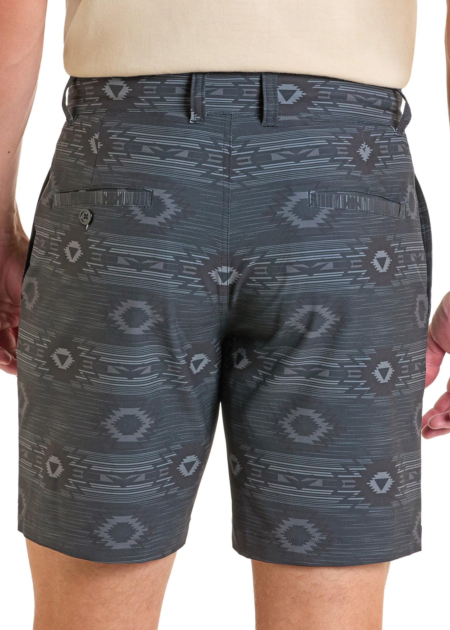 A person faces away from the camera wearing Rock & Roll Denim Aztec Printed Chino Shorts, featuring a geometric pattern, belt loops, and two buttoned back pockets.