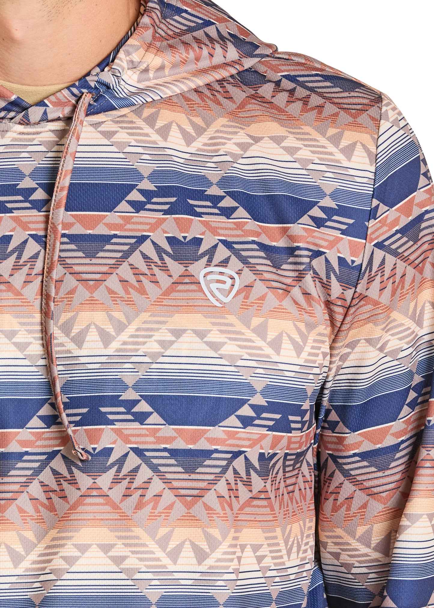 A person wears the Rock & Roll Denim Aztec Stripe Performance Hoodie, featuring a geometric tribal pattern in blue, peach, and beige with a small white chest logo and drawstrings. Only the upper body is visible.