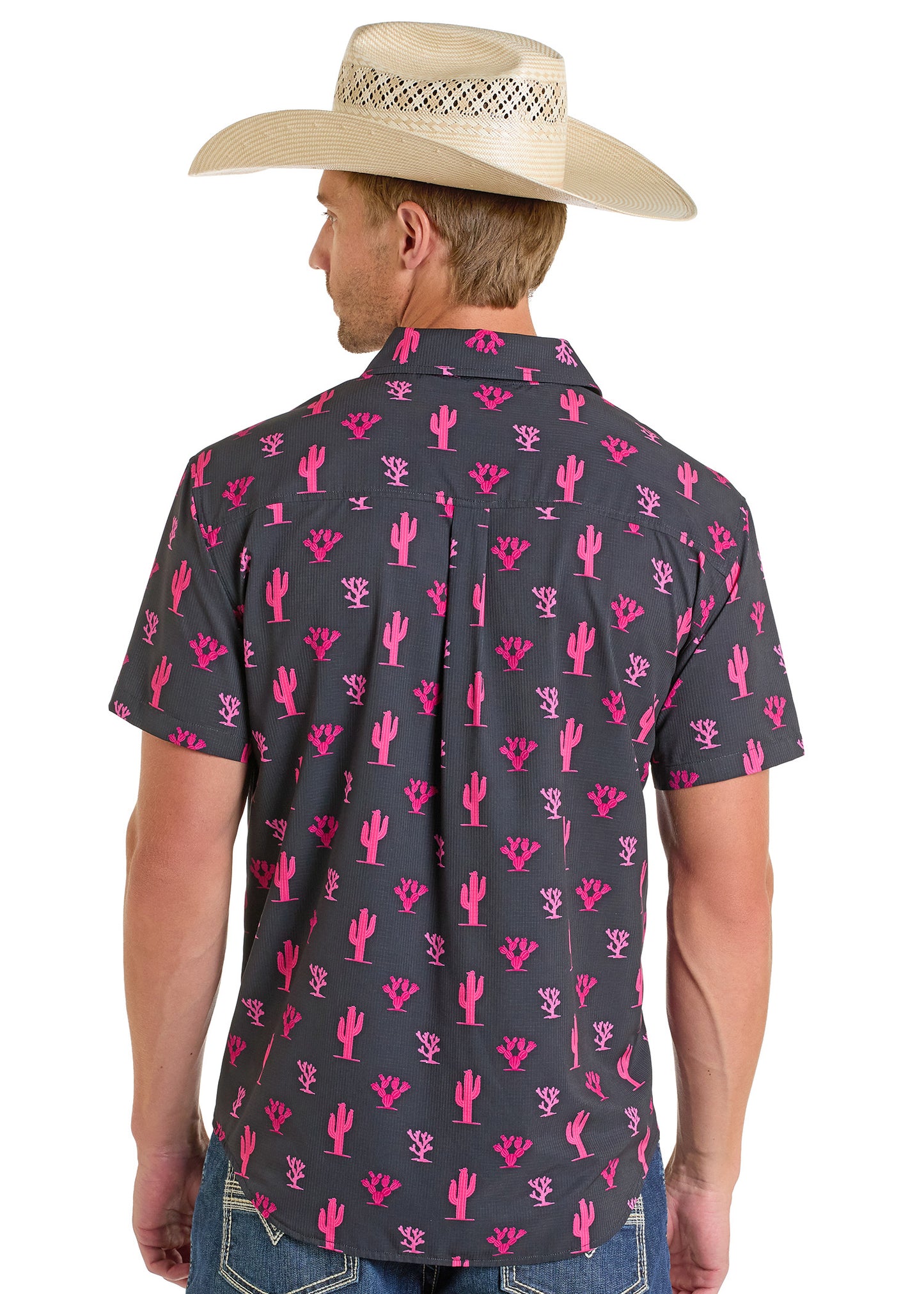 A man wearing a straw cowboy hat and a Rock & Roll Denim TEK Western Pink Cactus Short Sleeve Shirt stands facing away, highlighting the stylish back of his outfit.