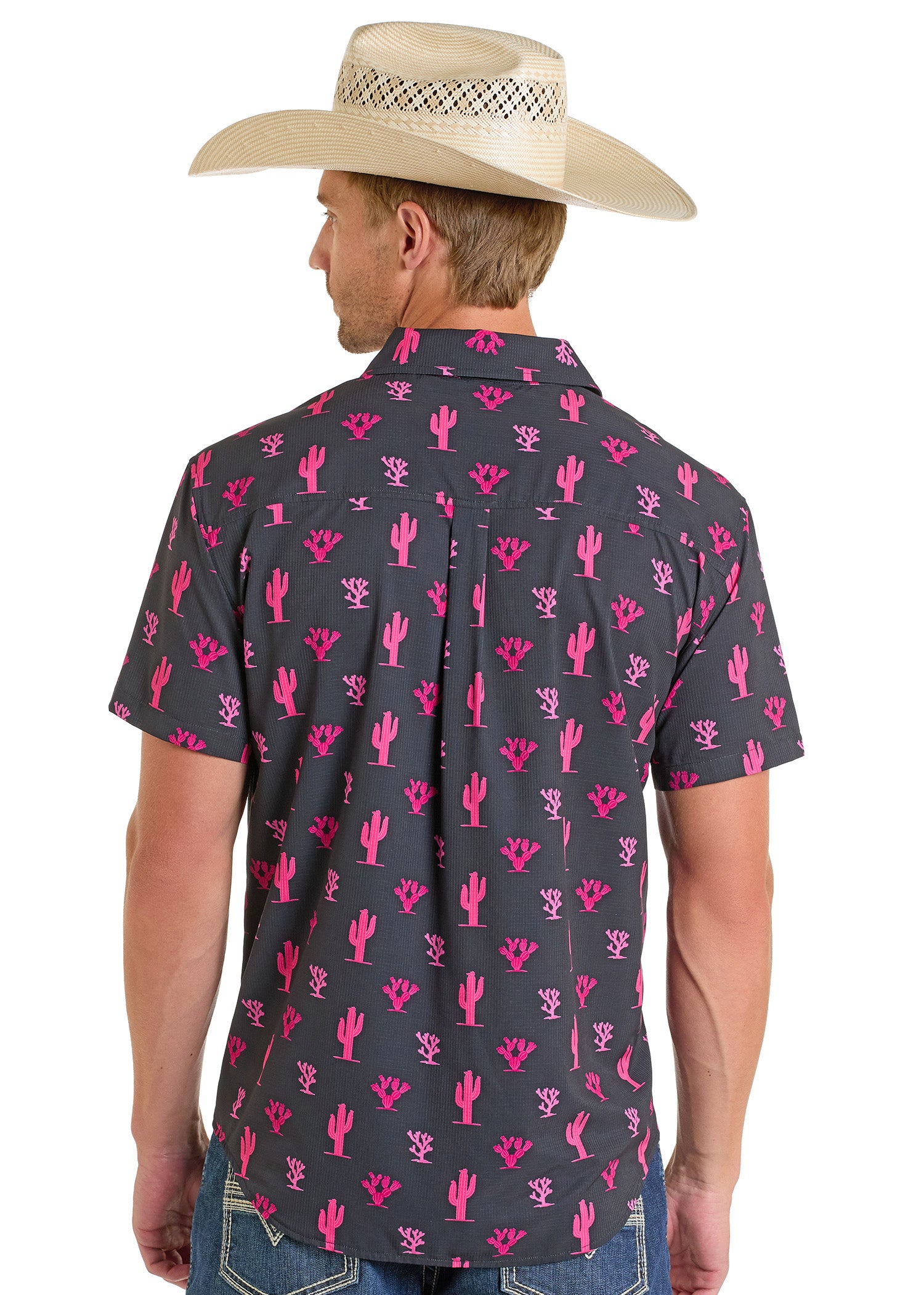 A man wearing a straw cowboy hat and a Rock & Roll Denim TEK Western Pink Cactus Short Sleeve Shirt stands facing away, highlighting the stylish back of his outfit.