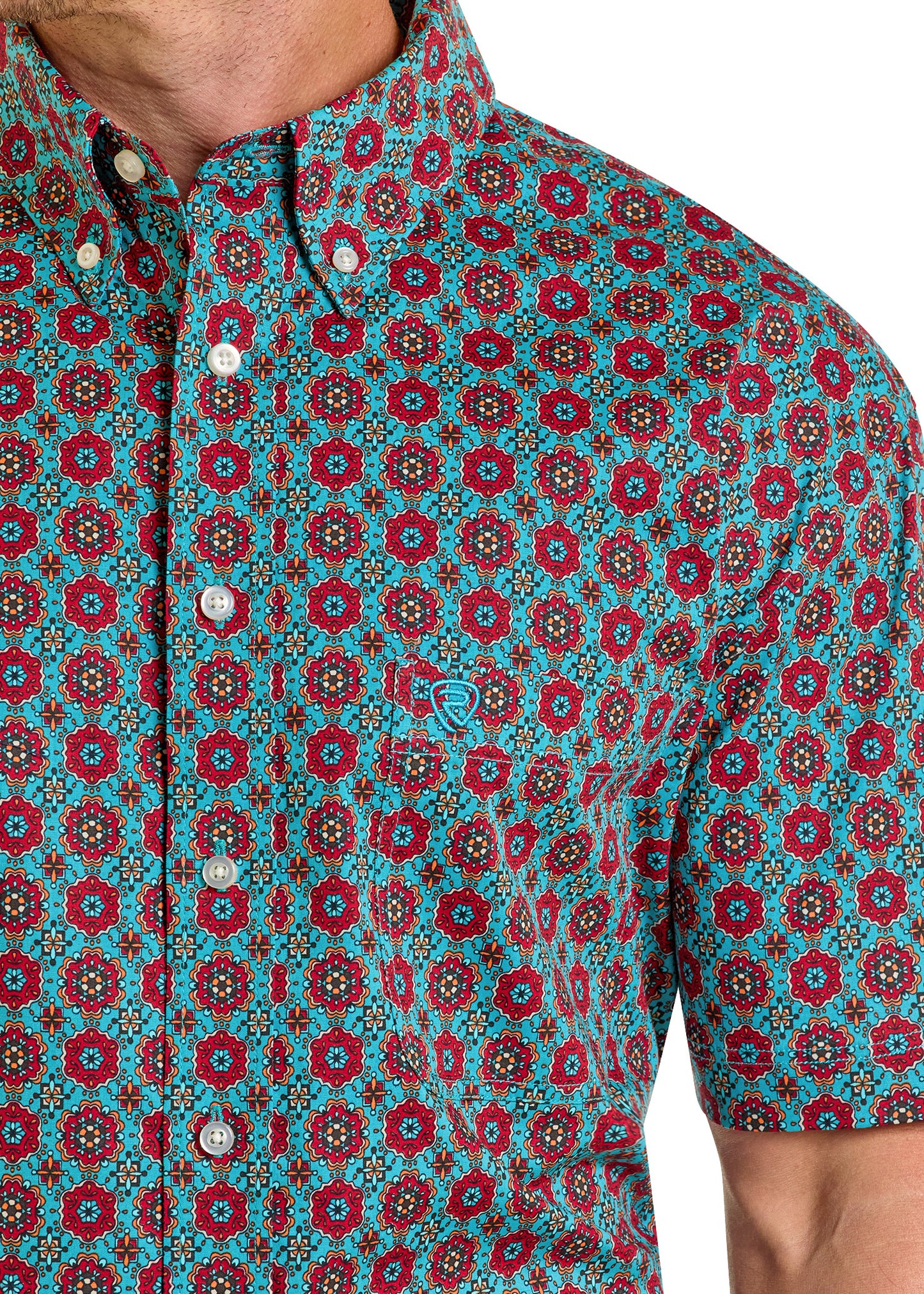 A person wears the Rock & Roll Denim Regular Fit Medallion Print Short Sleeve Button Shirt in red, teal, and yellow, featuring a small embroidered logo on the chest pocket.