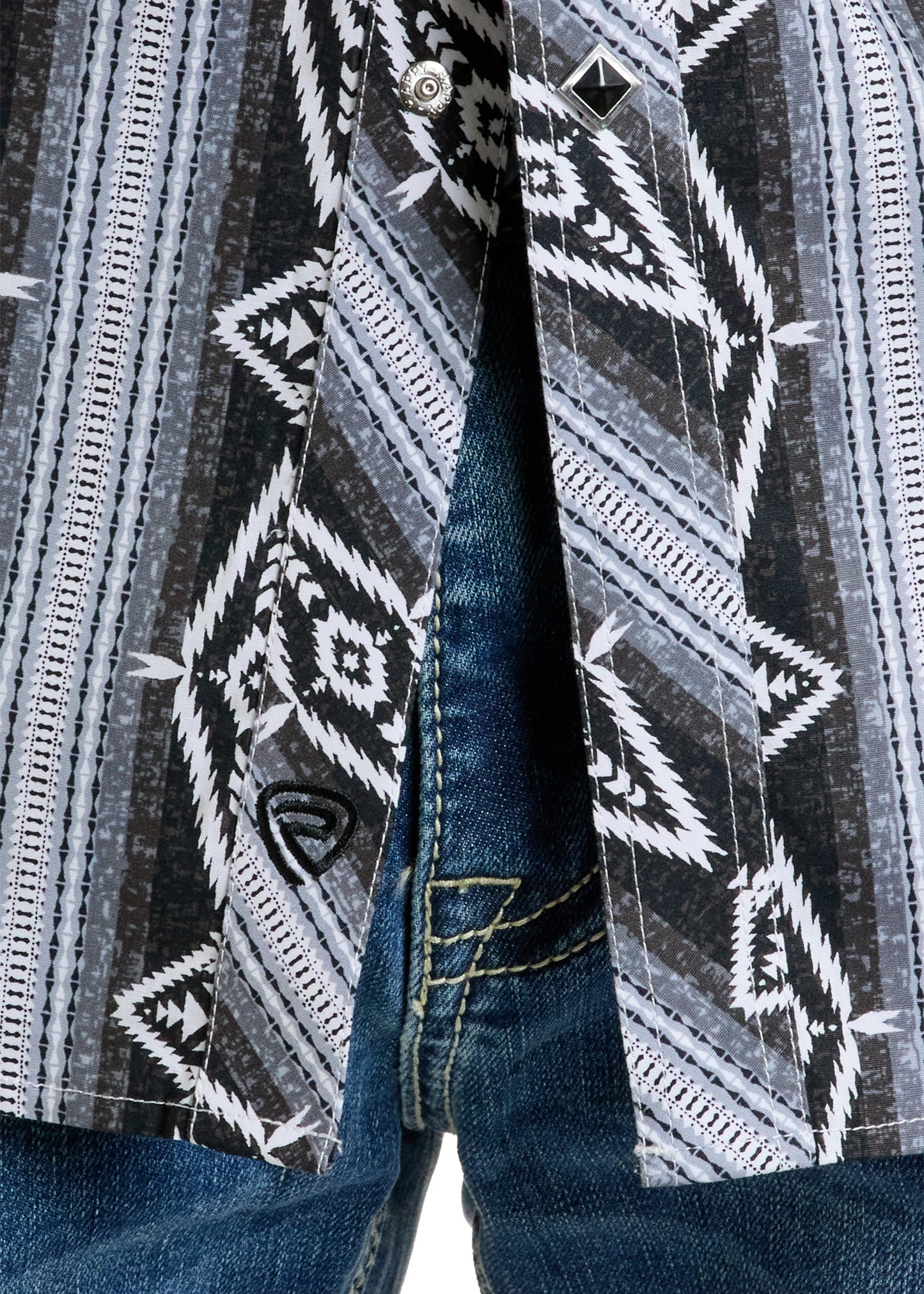 A close-up of a person in blue jeans and a Rock & Roll Denim Slim Fit Aztec Stripe Long Sleeve Snap Shirt with black, white, and gray geometric patterns. The shirt is partially unbuttoned, showing the jeans underneath.