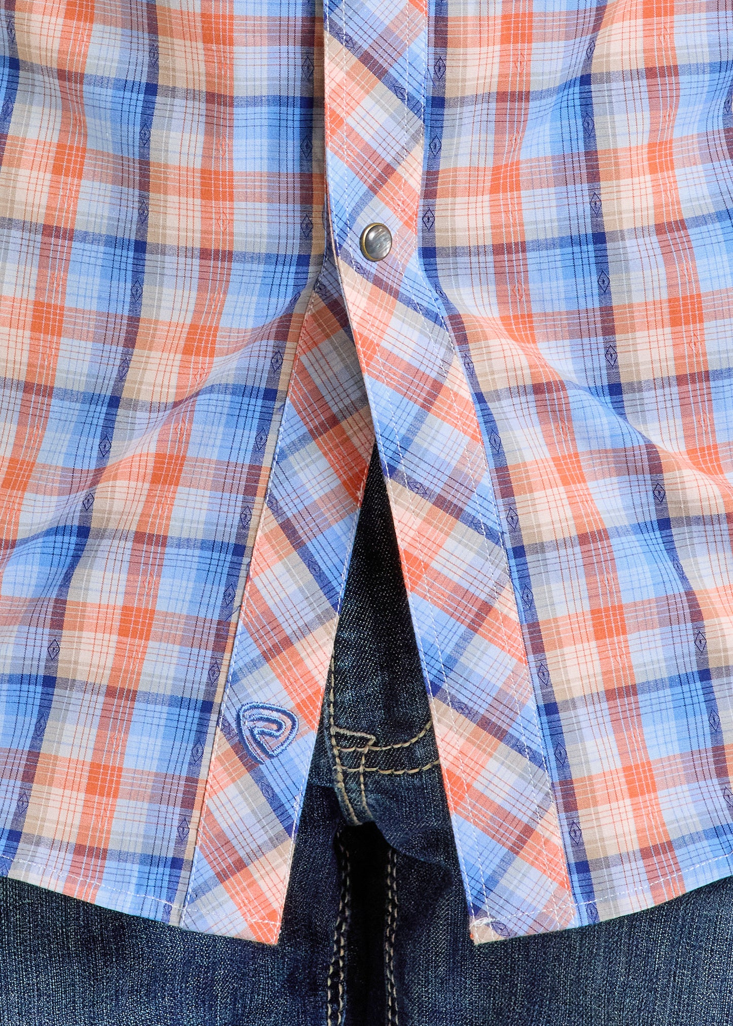 Close-up of a person in blue jeans and a Rock & Roll Denim Slim Fit Dobby Plaid Long Sleeve Snap Shirt - S, featuring blue, white, and red plaid pattern, with one snap button fastened and the shirt slightly open at the front.