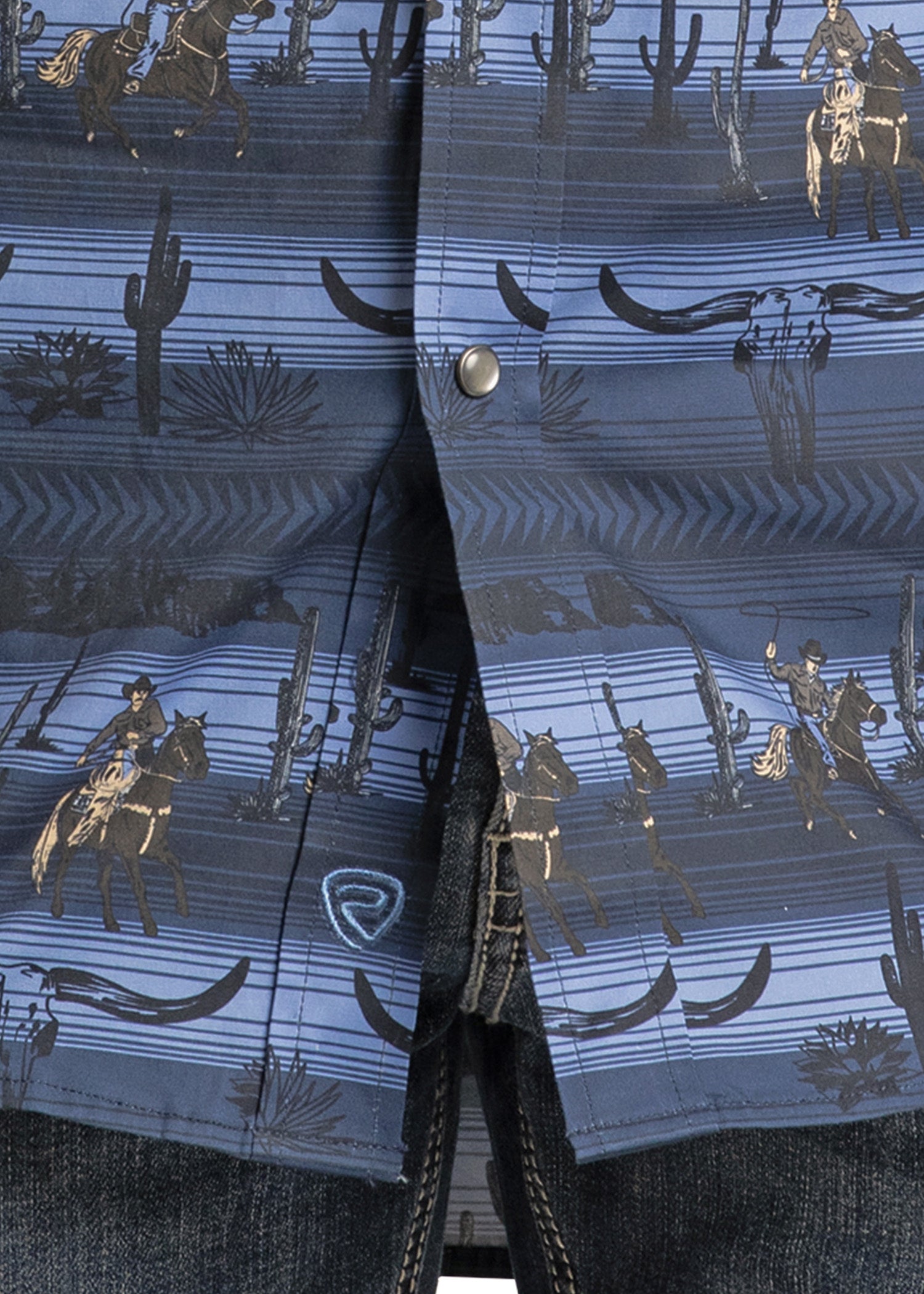 A close-up of the Rock & Roll Denim Slim Fit Longhorn Cowboy Long Sleeve Snap Shirt, showcasing a blue cowboy and cactus pattern with silver snaps, styled with dark denim jeans for a timeless Western look.