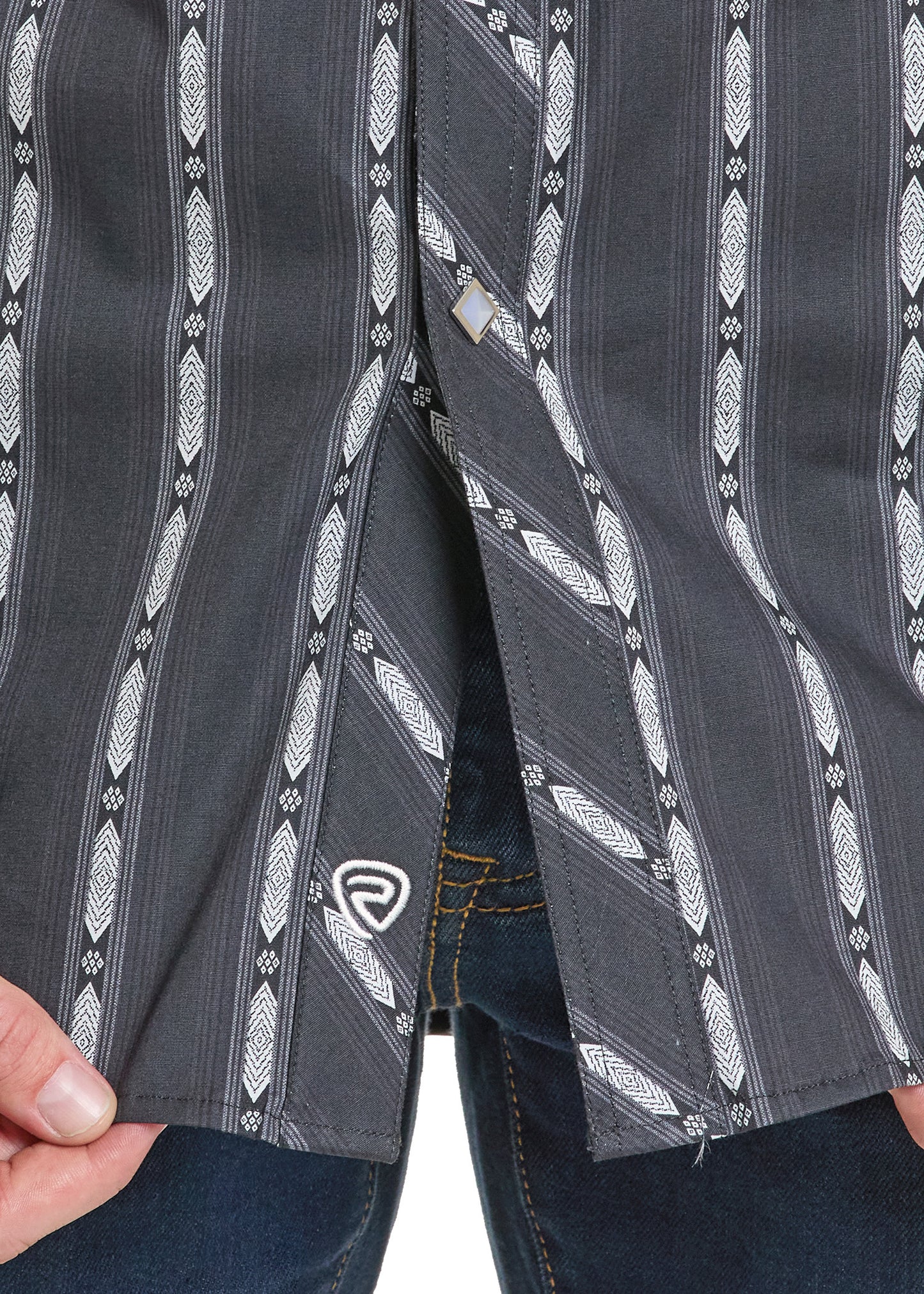 A close-up of a person wearing the Rock & Roll Denim Slim Fit Vertical Stripe Long Sleeve Snap Shirt with blue jeans, holding the hem. A small white logo appears on the lower part of the shirt.