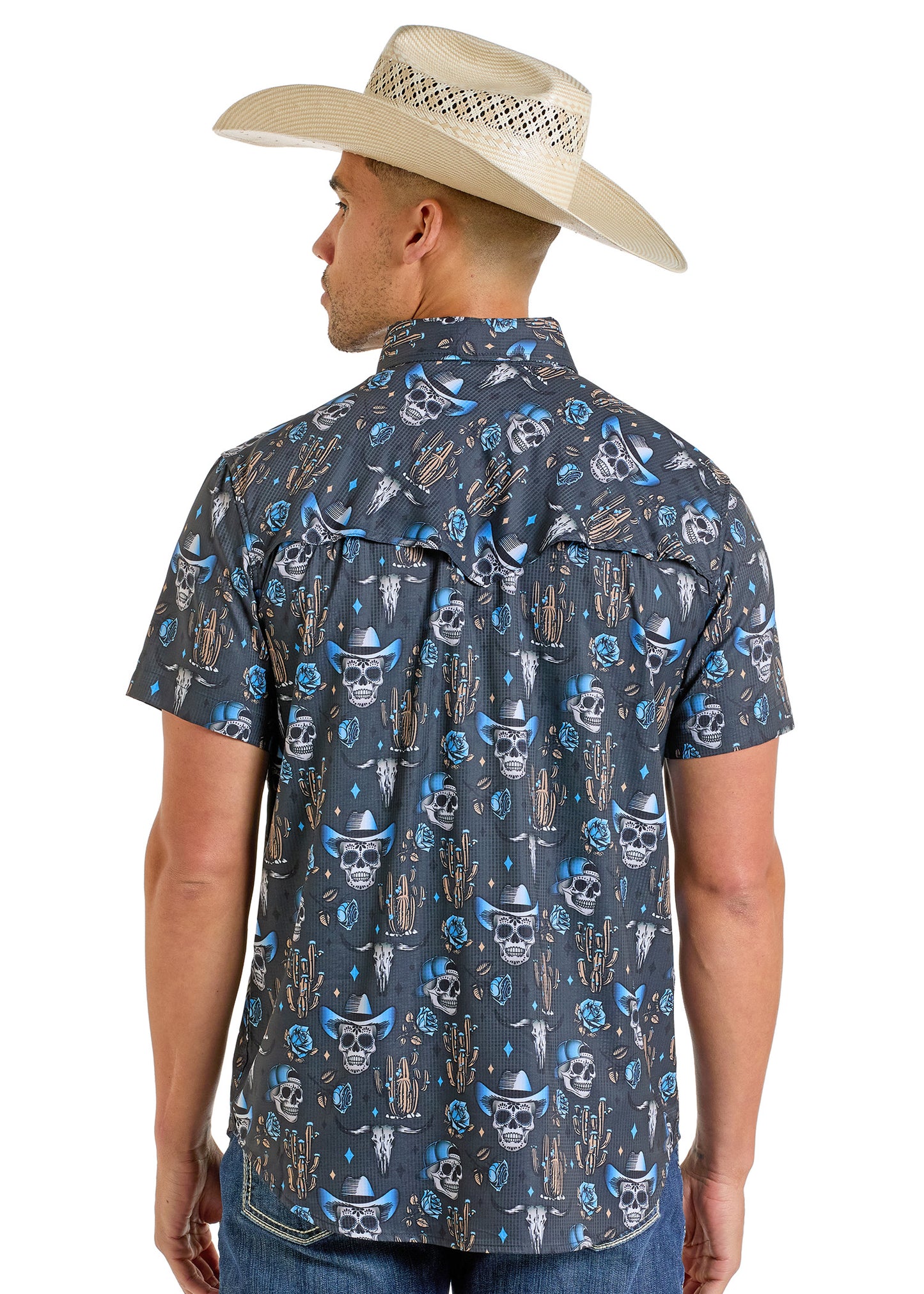 A man in a wide-brimmed straw cowboy hat and a Rock & Roll Denim TEK Western Skull Short Sleeve Shirt with a blue and white desert-themed pattern stands facing away, showcasing the shirt's moisture-wicking comfort.