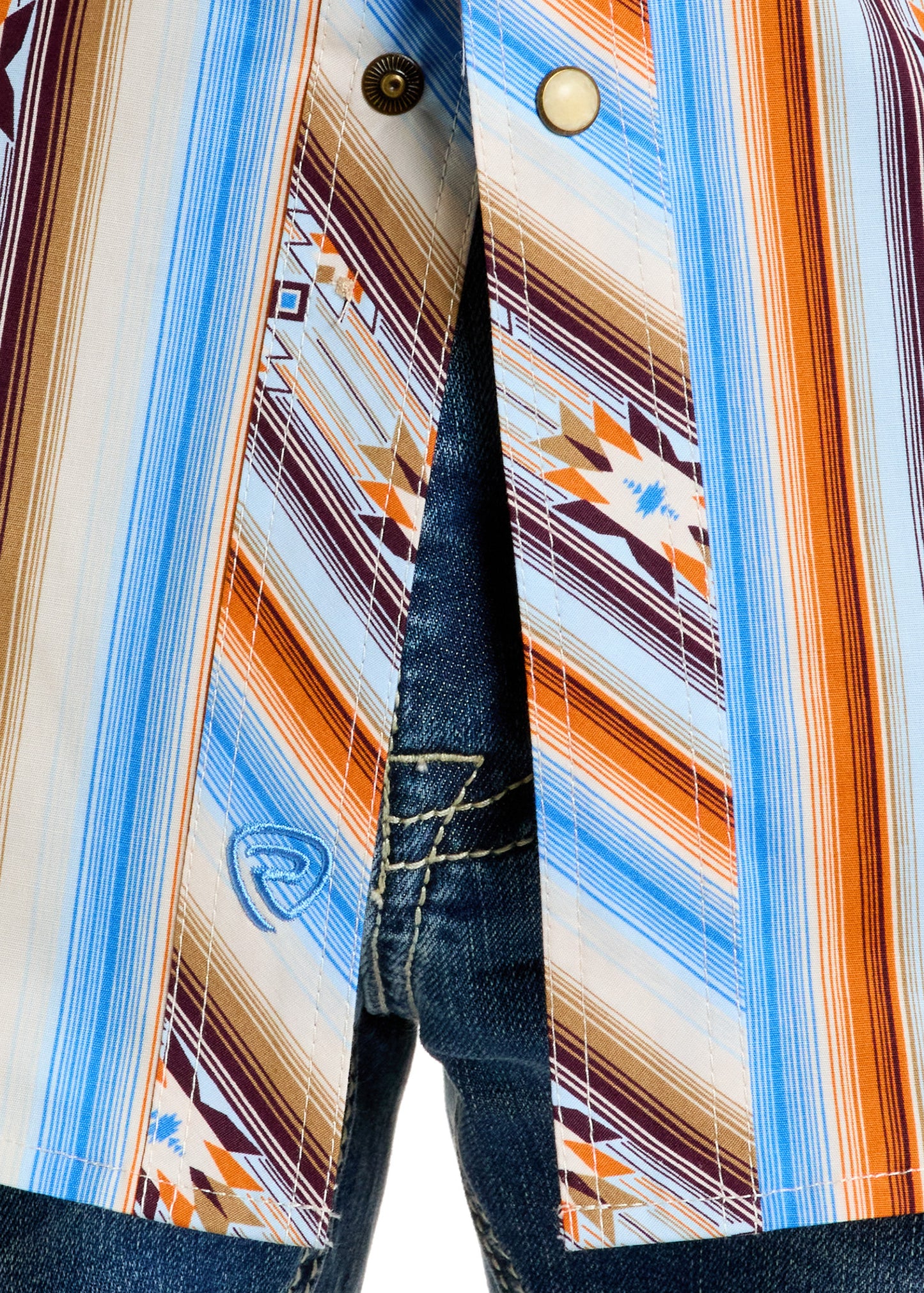 Close-up of a person in blue jeans and a Rock & Roll Denim Slim Fit Multi Aztec Short Sleeve Snap Shirt, featuring colorful blue, orange, brown, and white geometric vertical stripes. The shirt is unbuttoned at the bottom.