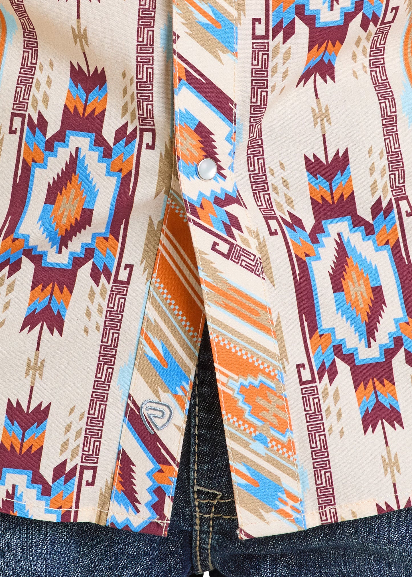 Close-up of the Dale Brisby Slim Fit Aztec Short Sleeve Snap Shirt by Rock & Roll Denim, featuring a bold Southwestern geometric pattern in blue, orange, red, and beige. Shirt is buttoned at the bottom and paired with blue jeans.