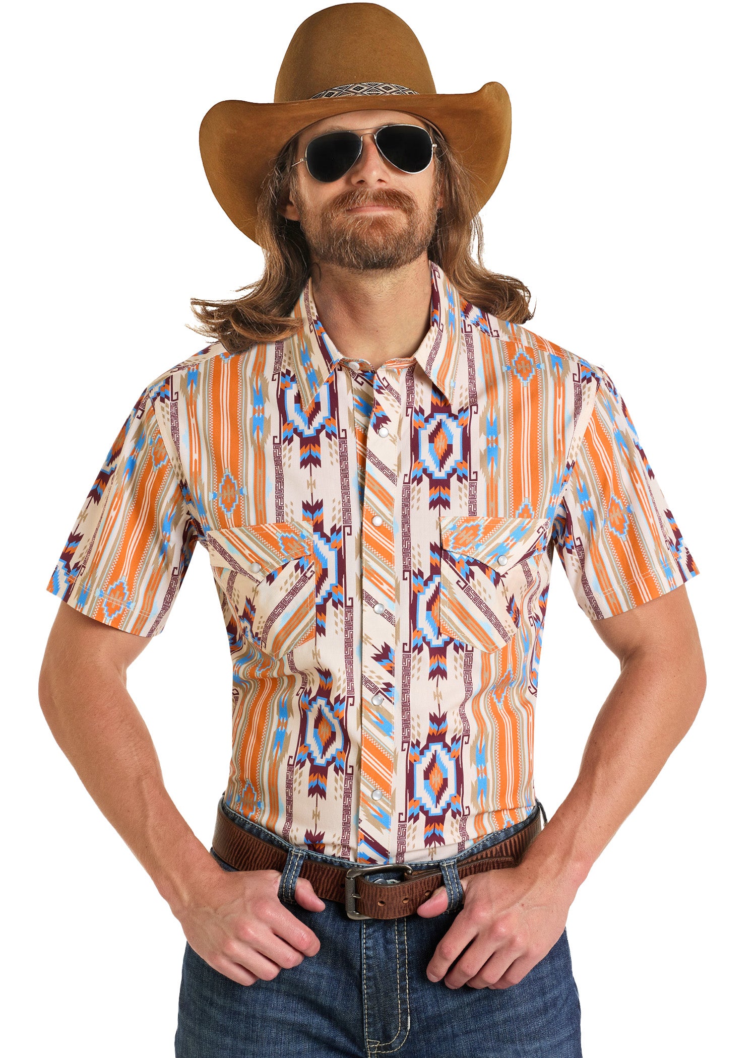 A man in a brown cowboy hat, sunglasses, and the Rock & Roll Denim Dale Brisby Slim Fit Aztec Short Sleeve Snap Shirt with orange, blue, and white patterns stands hands-on-hips, sporting long hair and a beard in classic Western style.
