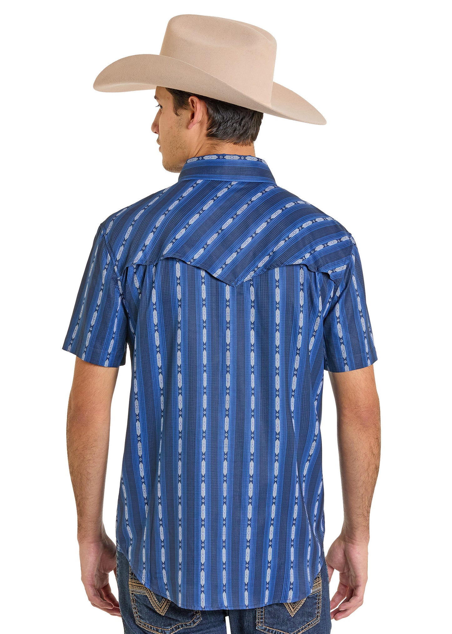 A man wearing a tan cowboy hat and the Rock & Roll Denim TEK Western Vertical Print Short Sleeve Shirt with UPF 50 stands with his back to the camera, paired with blue jeans for a classic, sun-smart look.