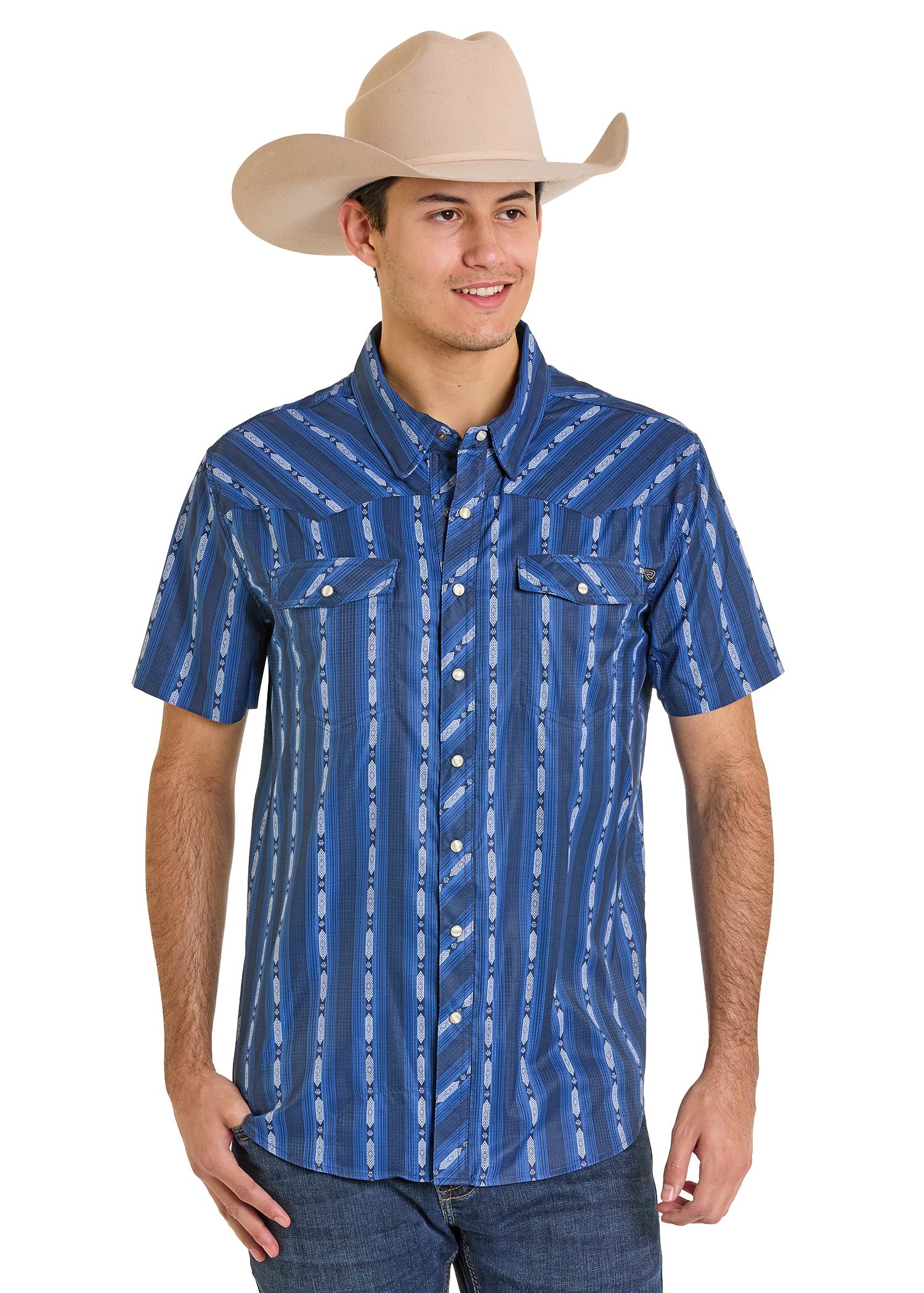 A man wearing a beige cowboy hat, jeans, and a Rock & Roll Denim TEK Western Vertical Print Short Sleeve Shirt with moisture-wicking fabric stands smiling with his hands relaxed by his sides.