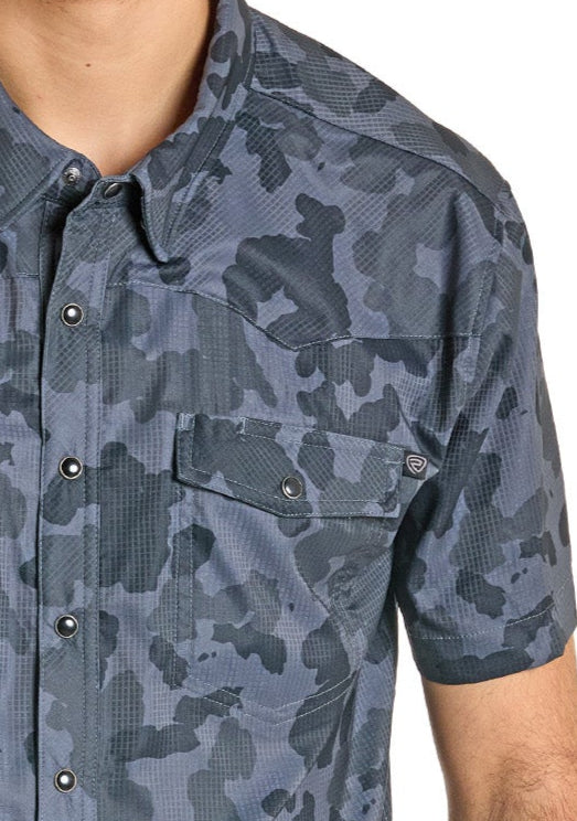 A person wears the Rock & Roll Denim TEK Western Black Camo Short Sleeve Shirt with moisture-wicking fabric, a front pocket, and metal snaps. Only the upper torso and part of the arm are visible.