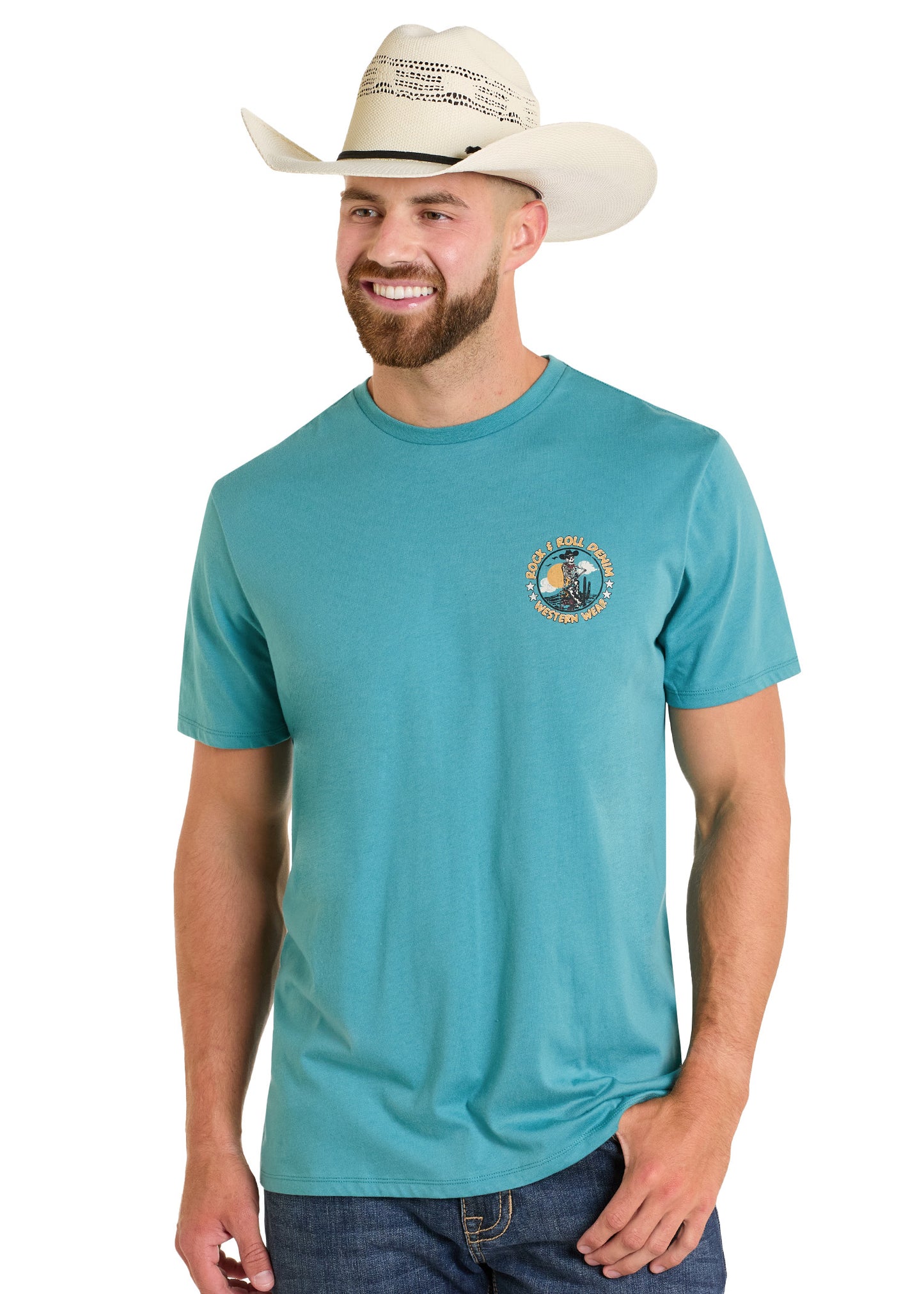 A smiling man wears the Rock & Roll Denim Cowboy Skeleton Graphic Tee with a small circular design, paired with a white cowboy hat and blue jeans, standing against a white background.