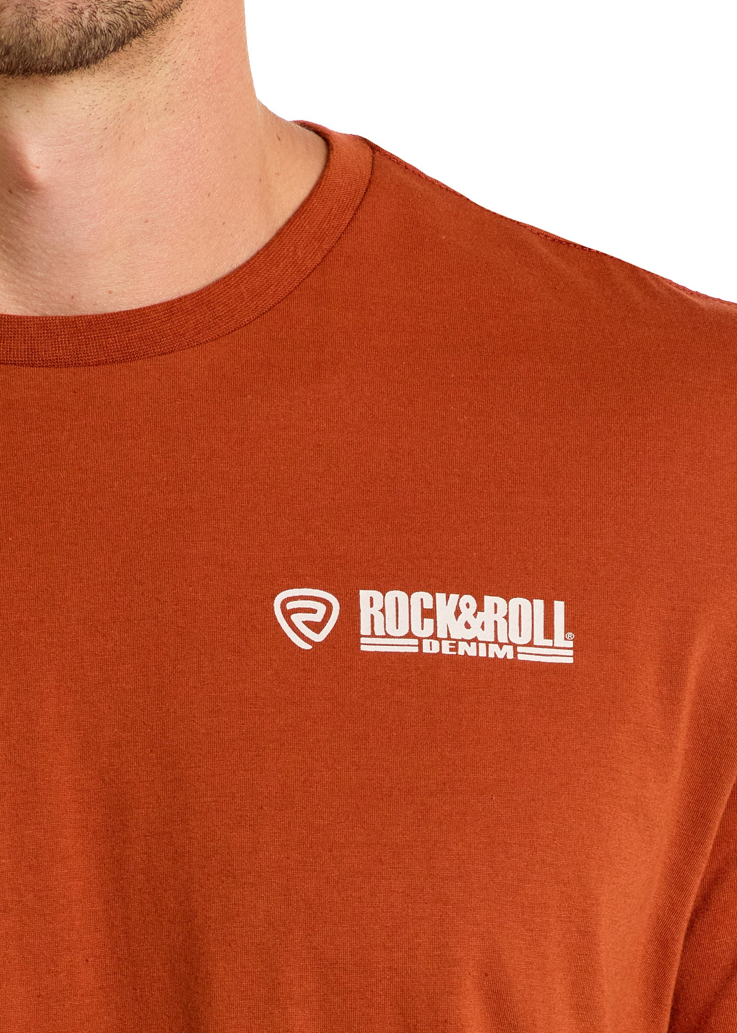 A person wears the Dale Brisby Rodeo Time Skull Graphic Tee by Rock & Roll Denim, featuring a rust color and white Rodeo Time graphic. Only the lower face, neck, and upper chest are visible.