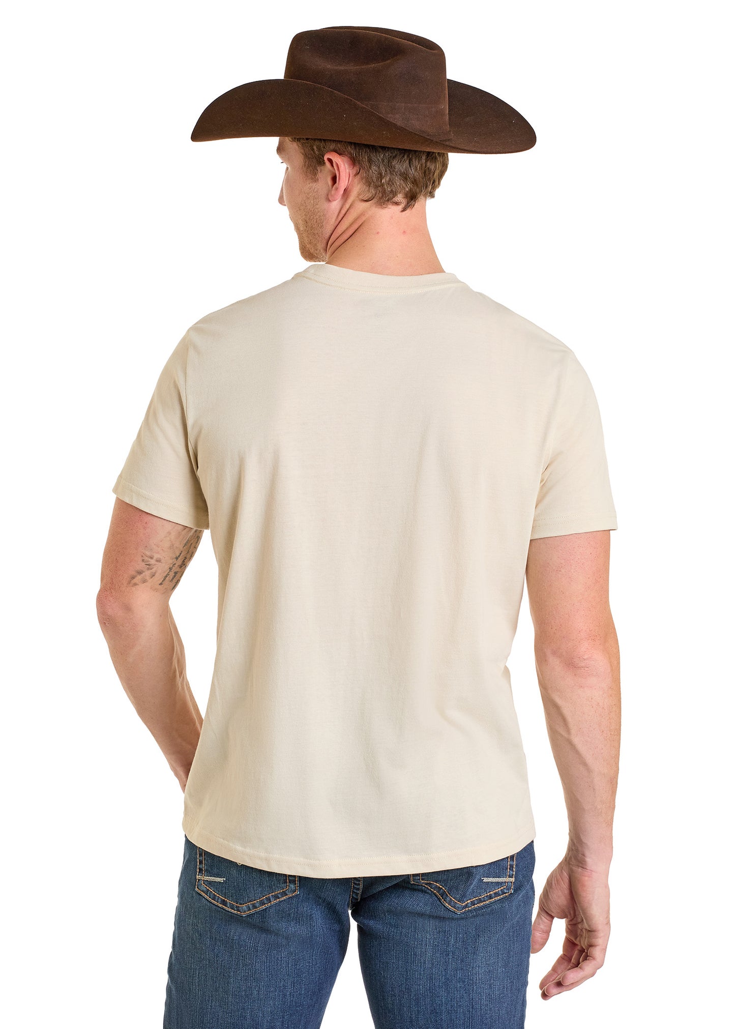 A man faces away, wearing a brown cowboy hat, comfy blue jeans, and a short-sleeve beige Rock & Roll Denim Let’s Get Rowdy Graphic Tee, showcasing the back of his everyday wear outfit.