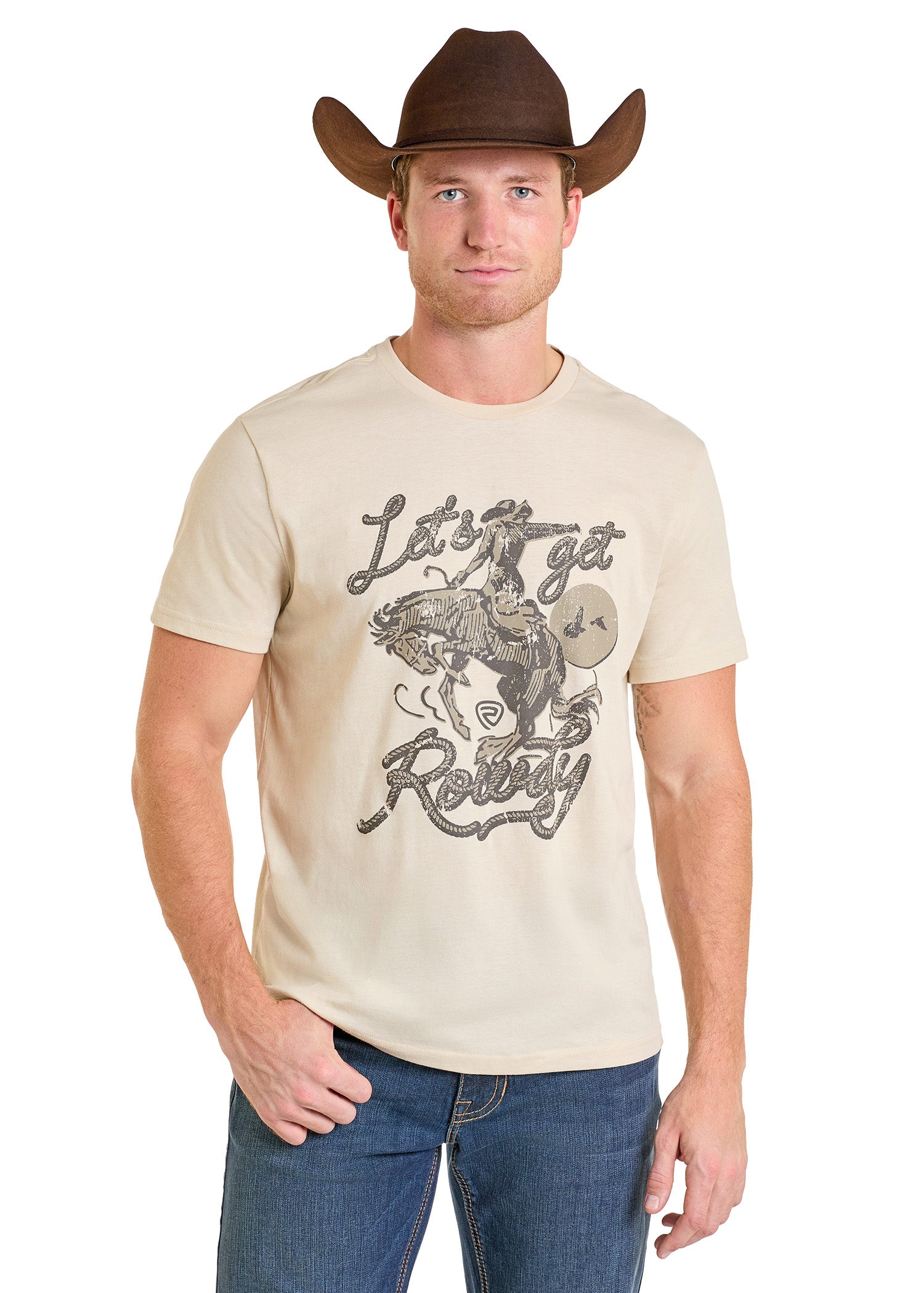 A man wears a brown cowboy hat, blue jeans, and the Rock & Roll Denim Let's Get Rowdy Graphic Tee featuring a bull rider design, standing forward with one hand in his pocket—ideal for comfort and everyday style.