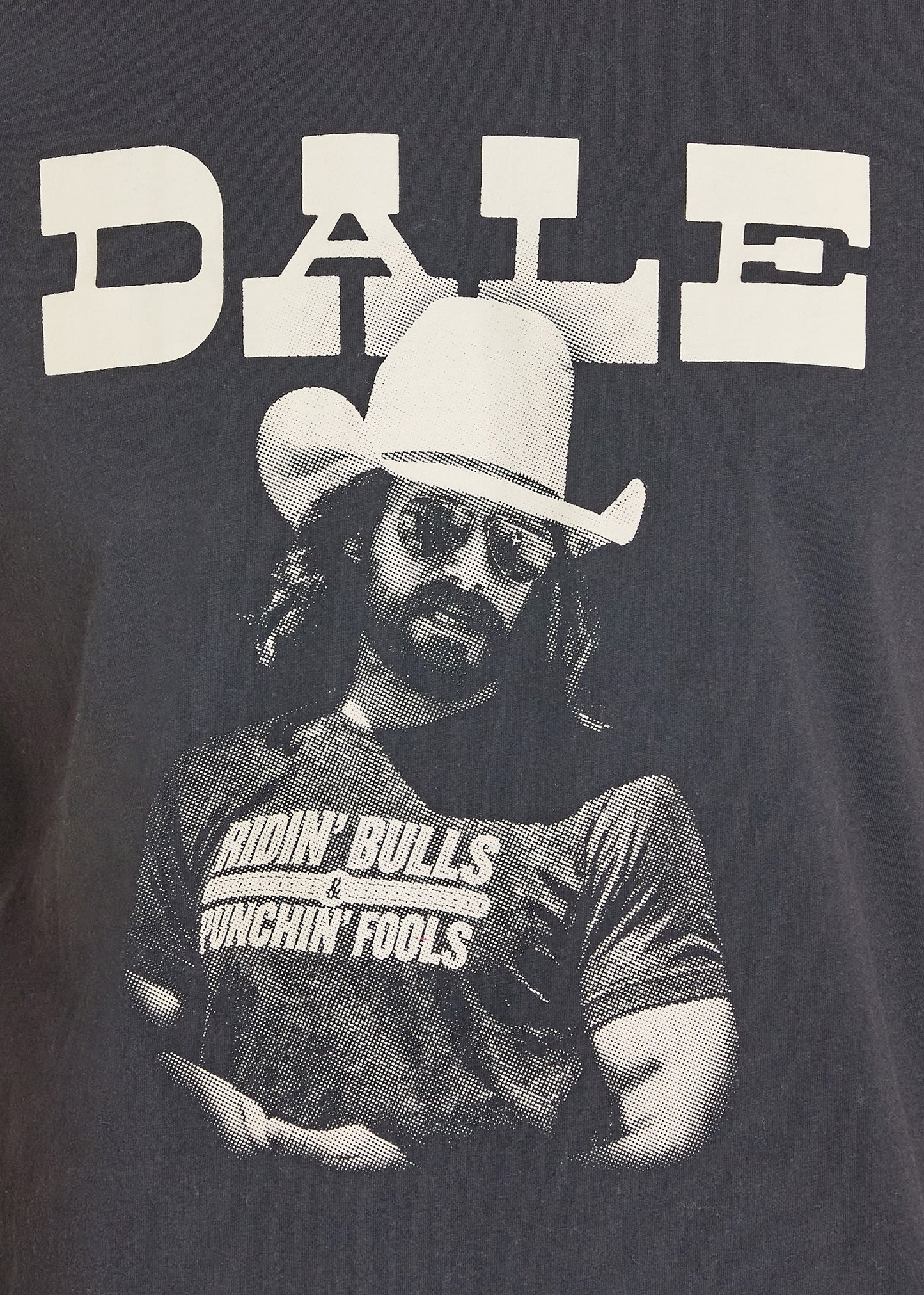 Person wearing a cowboy hat and graphic t-shirt with text on a dark background