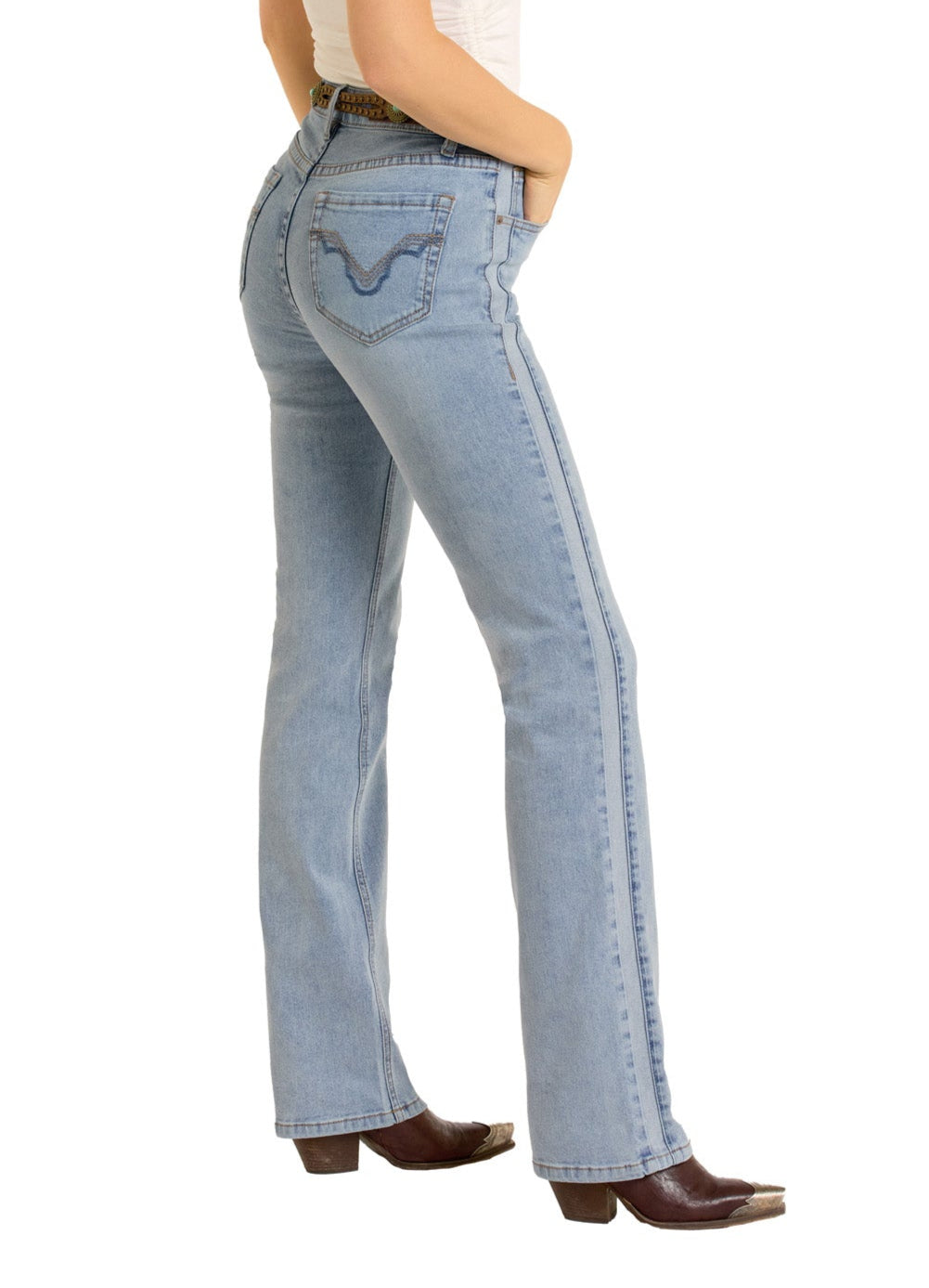 A person models Rock & Roll Denim’s Two-Tone Modest Bootcut Jeans in light blue, paired with a white top and brown heeled shoes, standing in profile with hands in pockets against a white background.