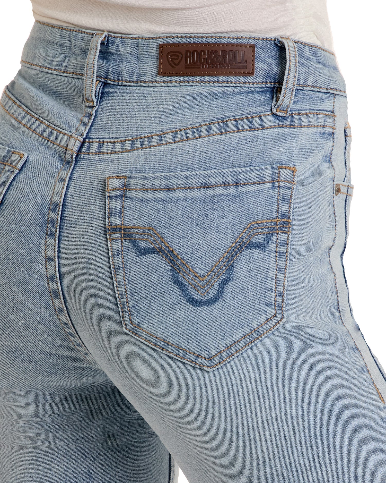 Close-up of a person wearing light blue Rock & Roll Denim Two-Tone Modest Bootcut Jeans. Visible stitching, a brown leather Rock & Roll Denim patch on the waistband, and a pocket with decorative stitched details are shown.