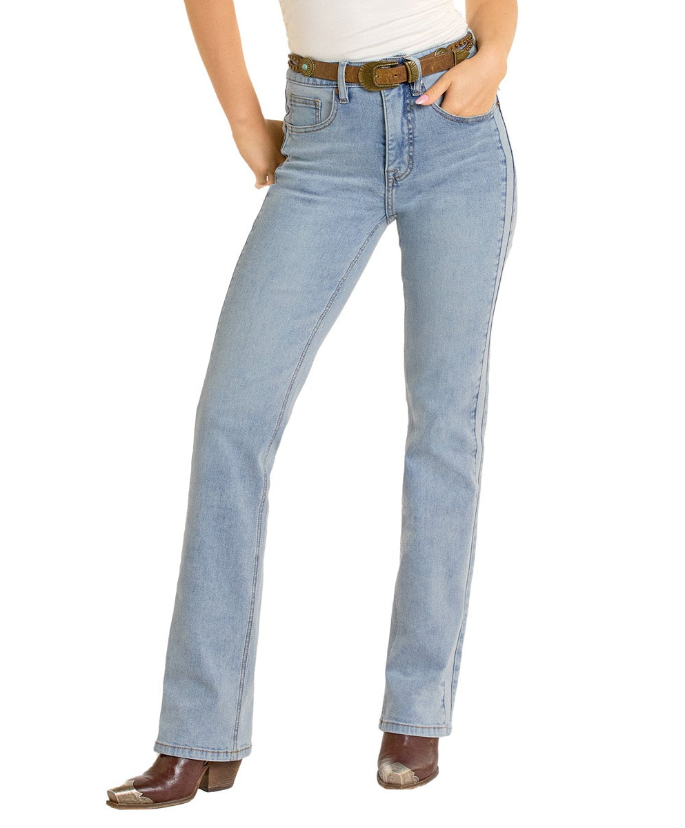 Someone wears Rock & Roll Denim Two-Tone Modest Bootcut Jeans, a brown belt, a white top, and brown cowboy boots. Their hands are in their pockets, and their head isn’t visible in the image.