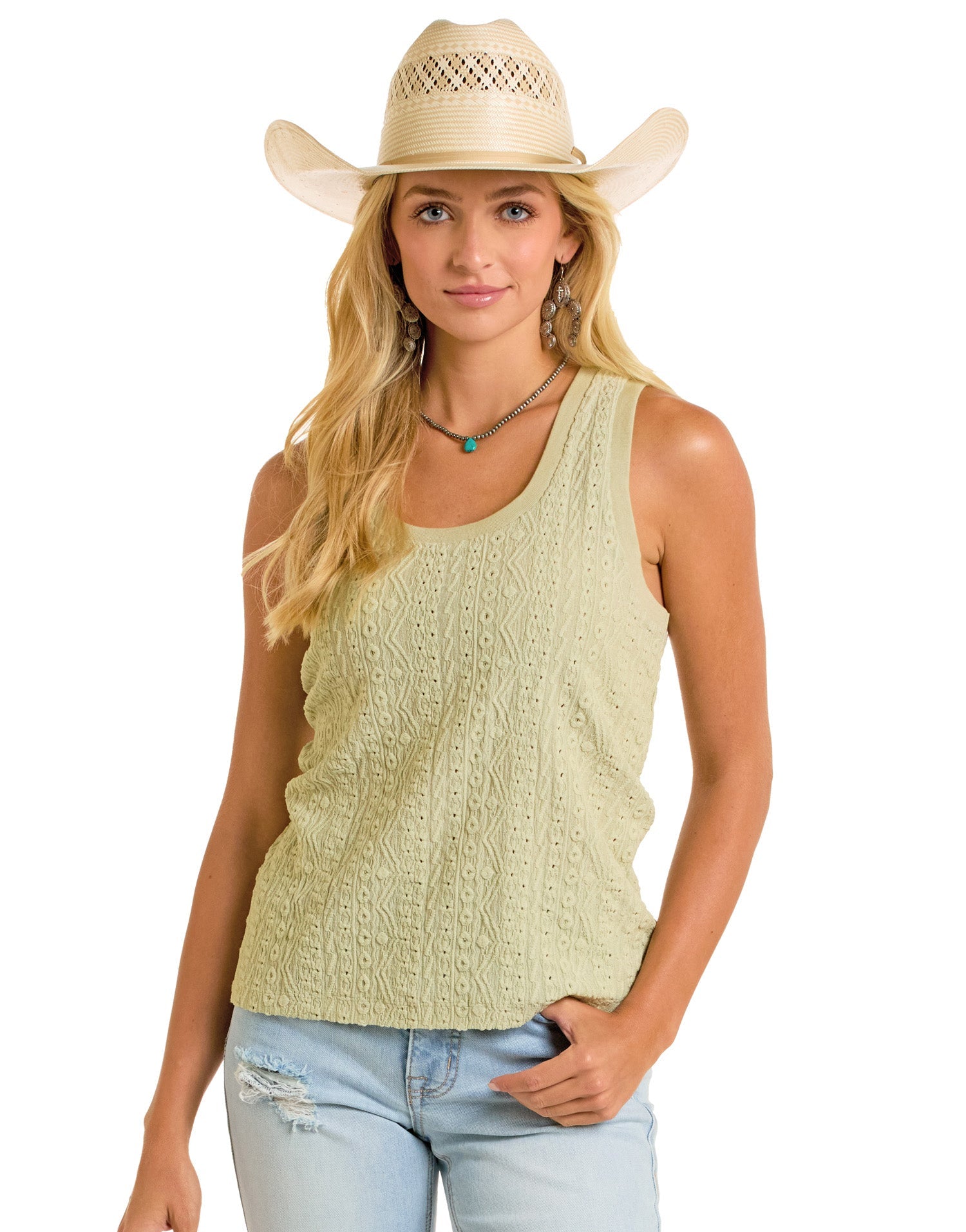 A woman in a Rock & Roll Denim Raised Knit Tank Top, distressed light blue jeans, and a straw cowboy hat stands with one hand in her pocket. She wears layered necklaces and earrings for a relaxed and casual look.