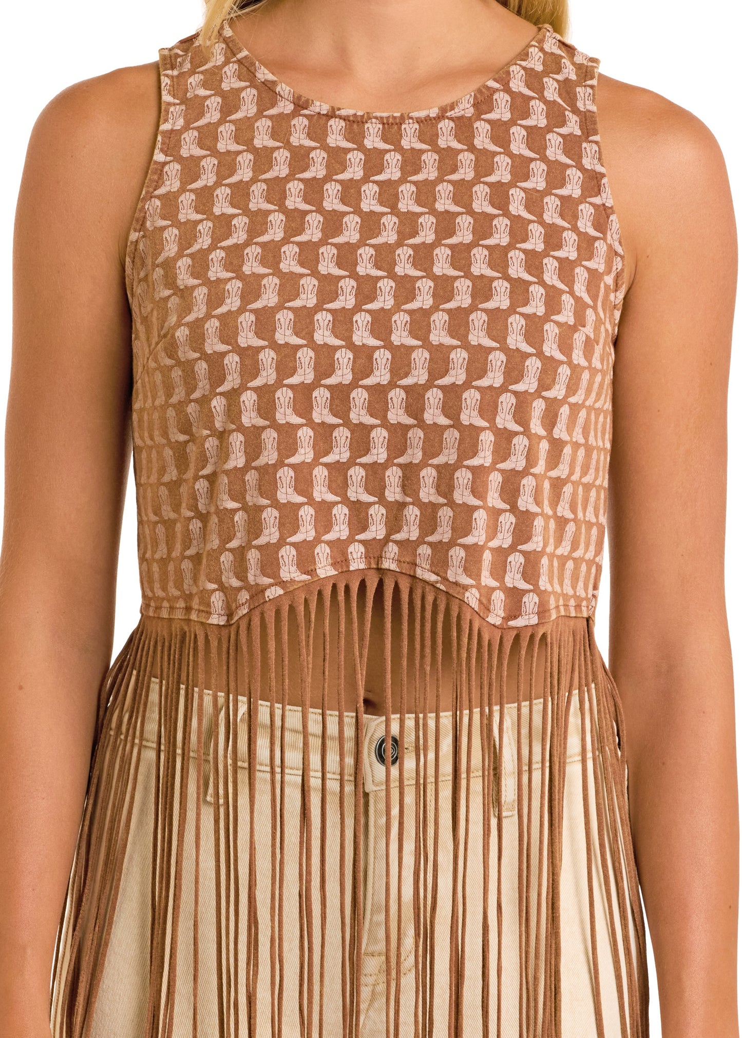 A person wears the Boot Print Fringe Top by Rock & Roll Denim—a sleeveless brown crop top with white geometric patterns and fringe at the hem—paired with light pants. The image is cropped at the shoulders and waist.