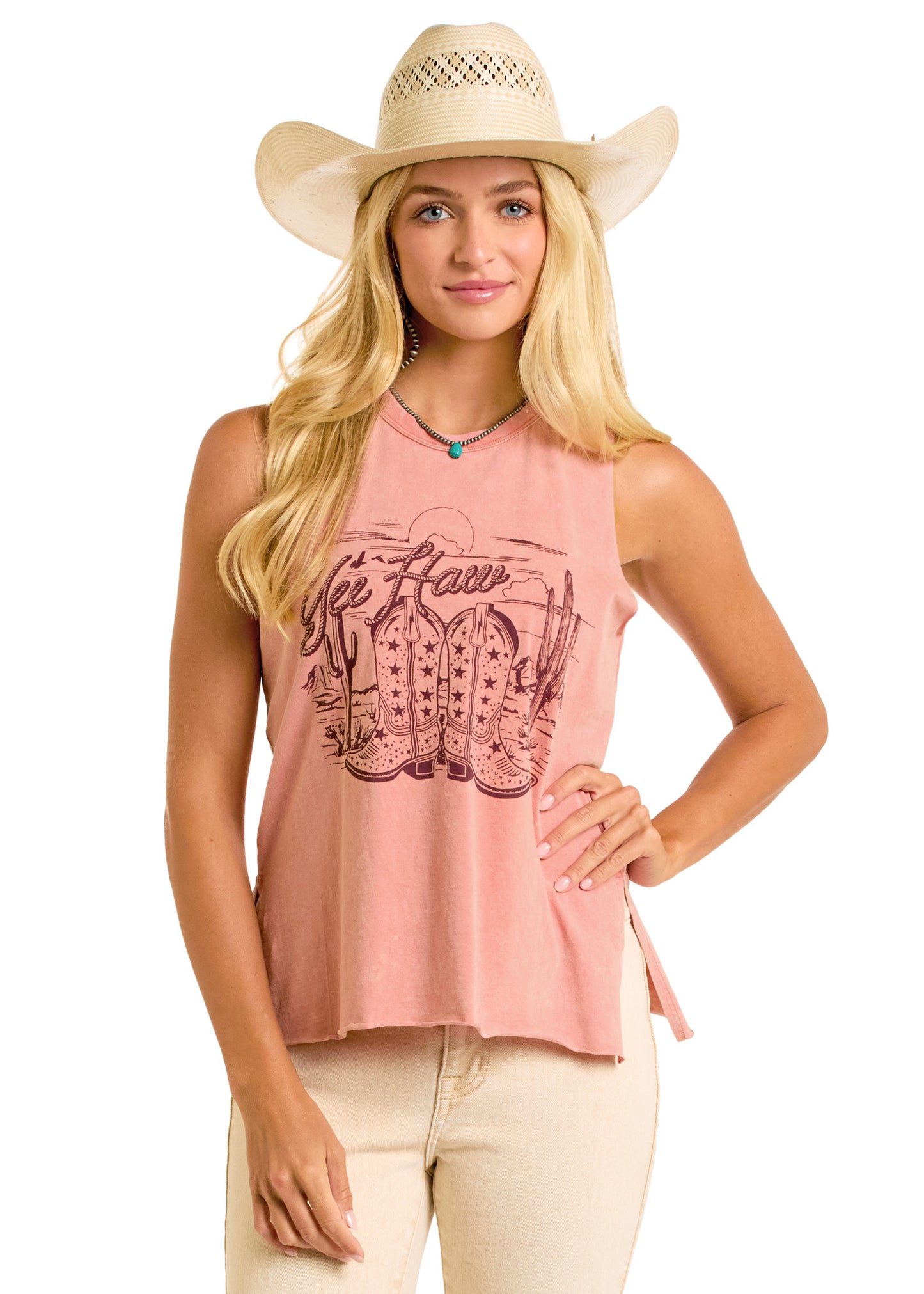 A woman stands facing forward and smiles, wearing a wide-brimmed cowboy hat, light-colored pants, and the Rock & Roll Denim Yee Haw Graphic Tank featuring cowboy boots and cacti.