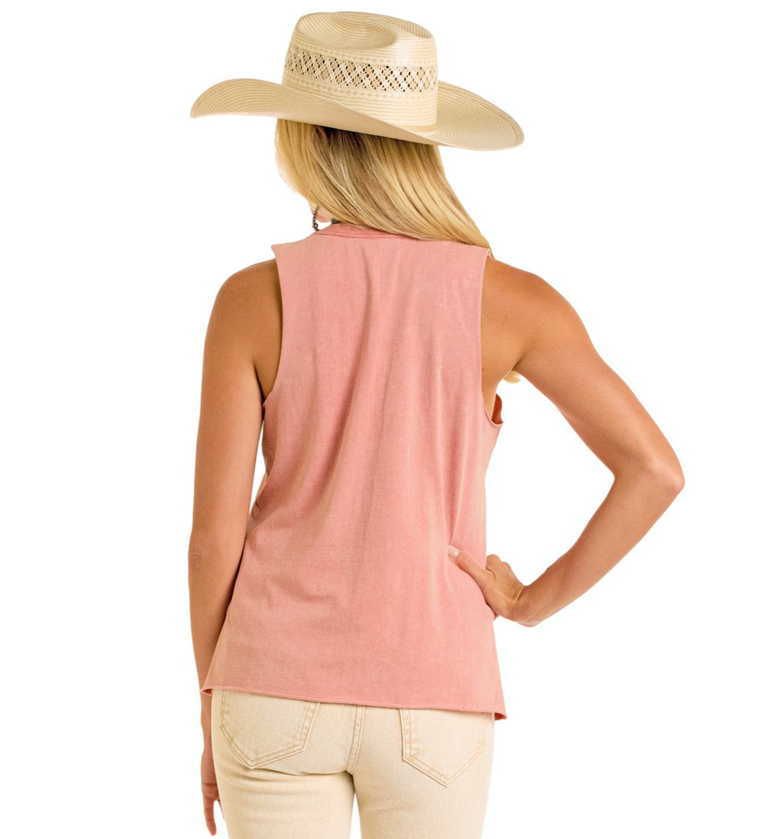 A woman with long blonde hair, in a wide-brimmed straw hat, beige pants, and a Rock & Roll Denim Yee Haw Graphic Tank, stands facing away with one hand on her hip against a white background.