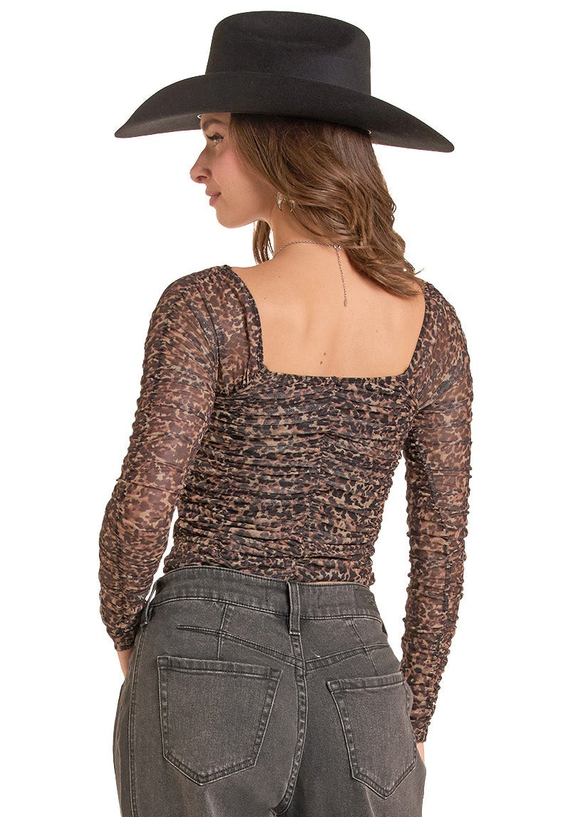 A woman shown from the back wearing a black wide-brim hat, a brown and black patterned long-sleeve top.