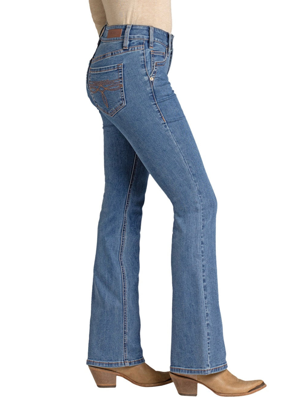 A person stands sideways on a white background wearing Rock & Roll Denim's Mid Rise Classic Boot Embroidered Bootcut Jean with visible stitching and back pockets, paired with tan heeled boots.