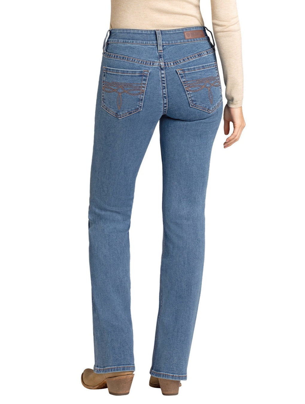 A person wearing Rock & Roll Denim's Mid Rise Classic Boot Embroidered Bootcut Jean, a beige long-sleeve top, and brown shoes stands with their back to the camera, showing off the jeans' embroidered back pocket designs.
