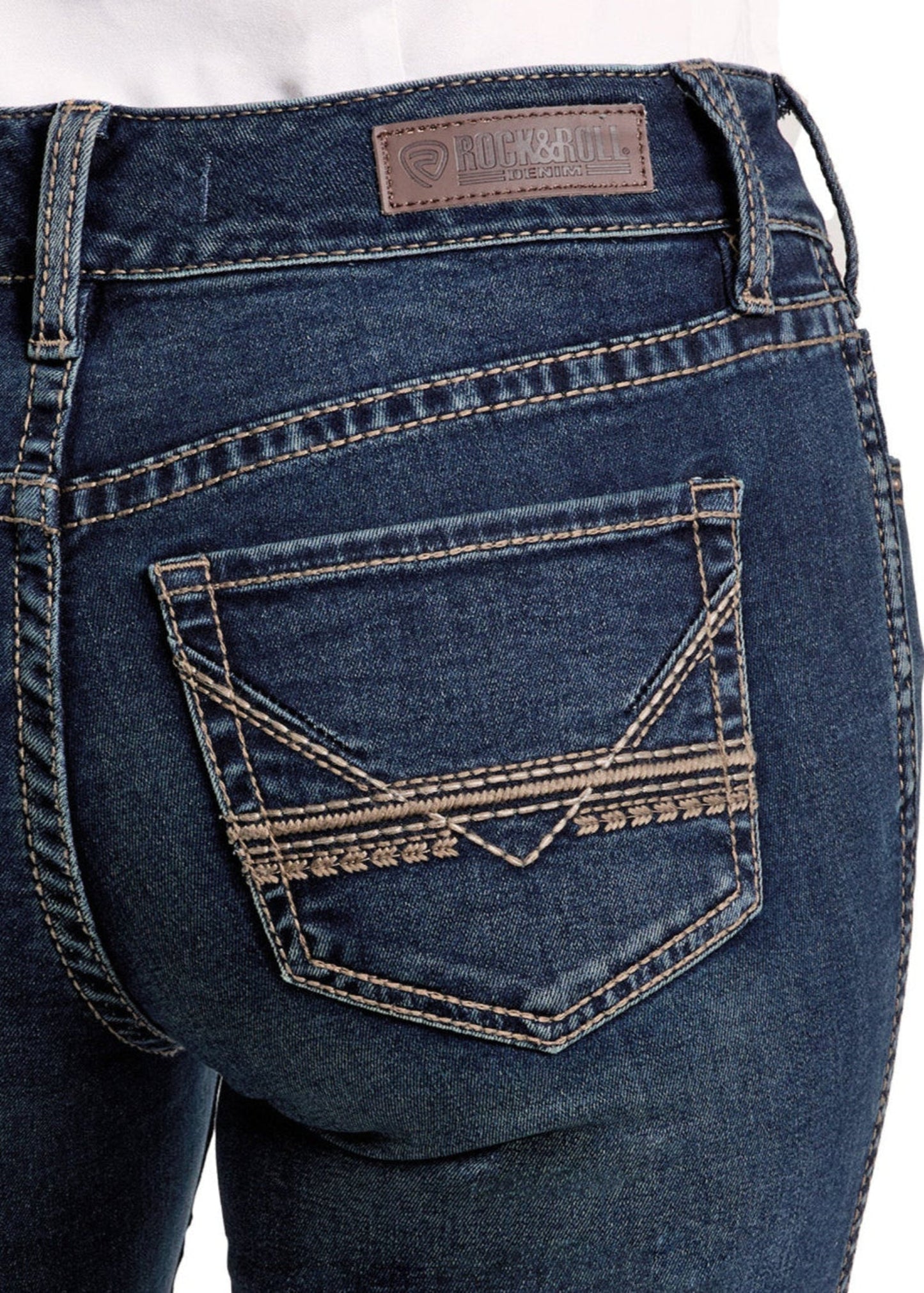 Close-up of the back pocket on Rock & Roll Denim’s Mid Rise Classic Stitch Bootcut Riding Jeans, featuring decorative stitching and a brown leather label. The jeans are modeled with a white shirt.