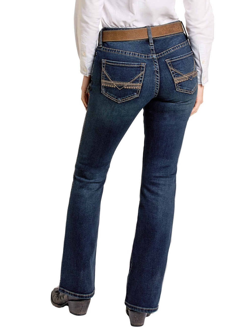 A person is shown from the back, standing with legs slightly apart, wearing Rock & Roll Denim Mid Rise Classic Stitch Bootcut Riding Jeans in dark blue and a white long-sleeve shirt. The jeans feature decorative stitching on the back pockets.