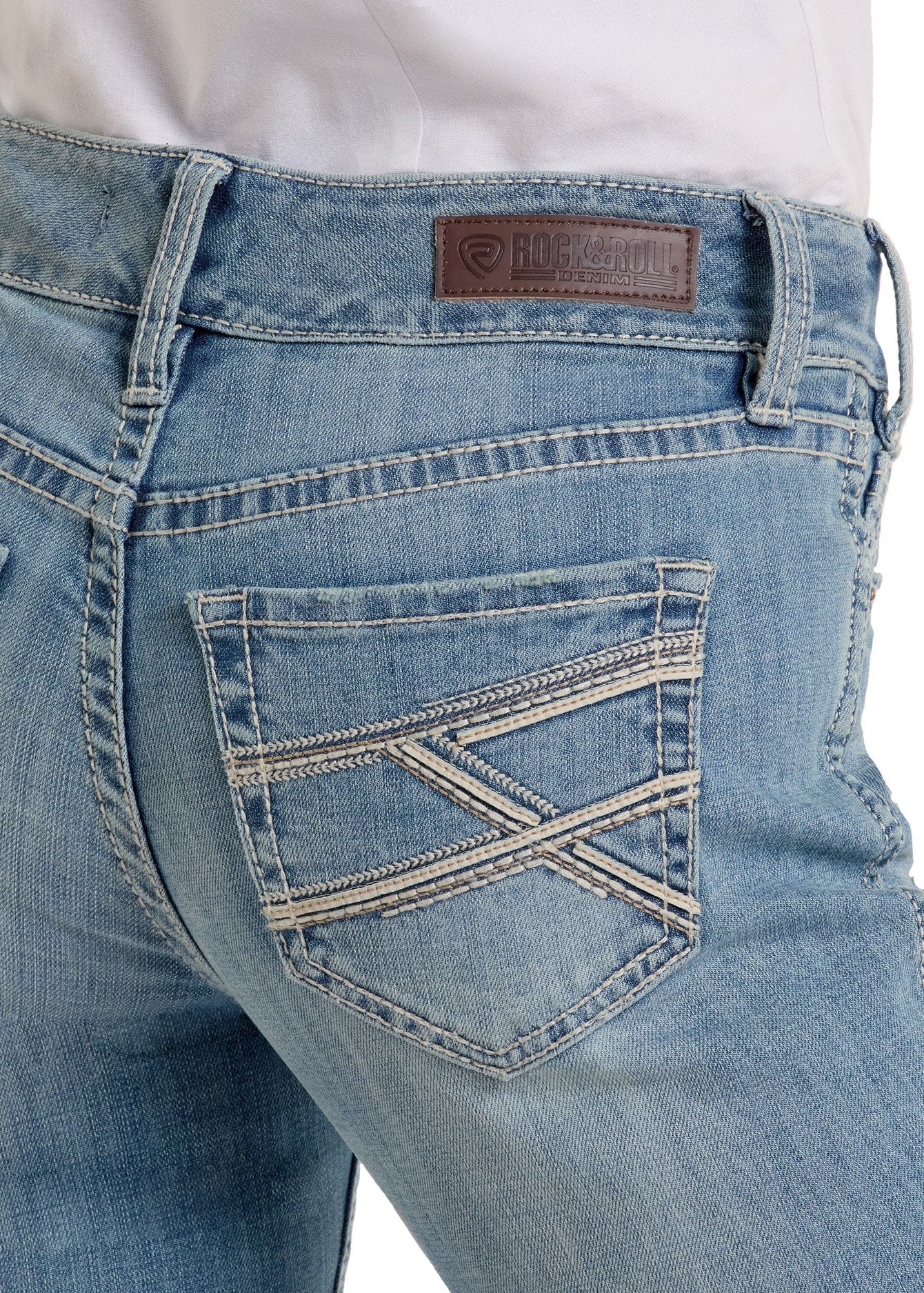 Close-up of the back of a person wearing light blue Mid Rise Cross Stitch Bootcut Riding Jeans with decorative pocket stitching and a brown leather Rock & Roll Denim brand patch on the waistband.