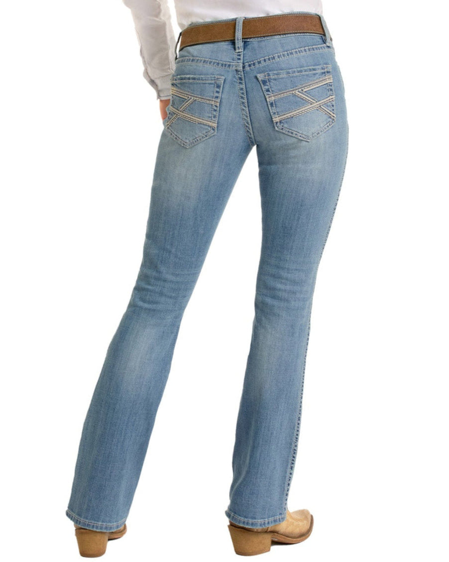 A person wearing Rock & Roll Denim's Mid Rise Cross Stitch Bootcut Riding Jeans, styled with a brown belt, tan boots, and a white shirt. The rear view highlights the jeans' full length and decorative back pocket stitching.