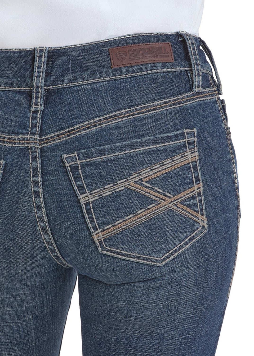 Close-up of the back of a person wearing Rock & Roll Denim Mid Rise Cross Stitch Bootcut Riding Jeans, featuring a brown leather patch, decorative cross stitching on the pockets, contrast stitching, and a visible belt loop.