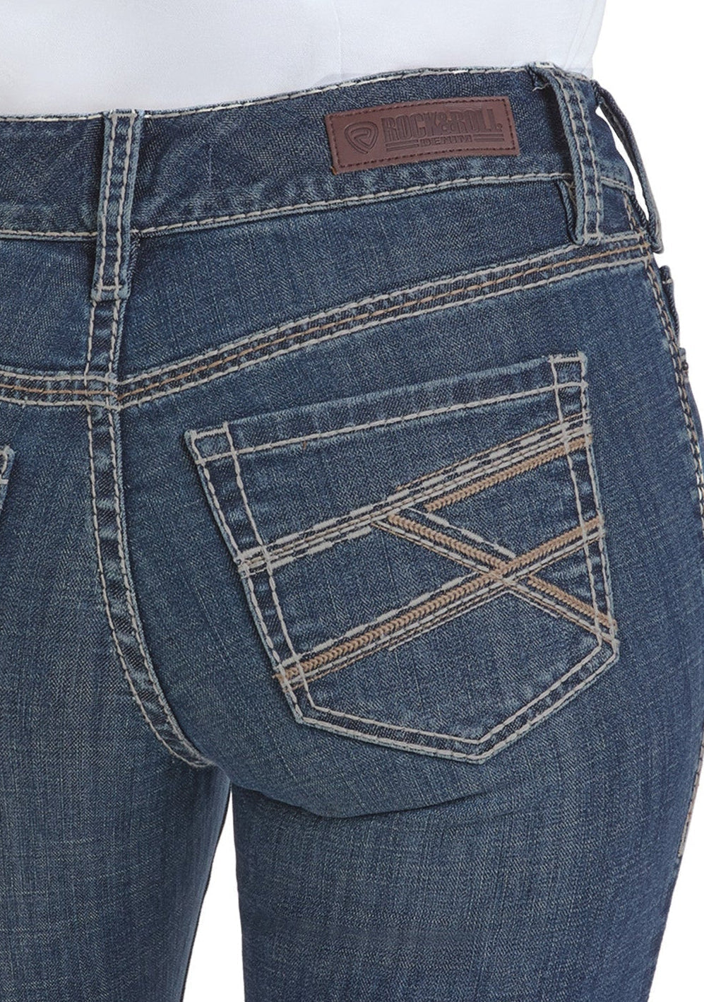 Close-up of the back of a person wearing Rock & Roll Denim Mid Rise Cross Stitch Bootcut Riding Jeans, featuring a brown leather patch, decorative cross stitching on the pockets, contrast stitching, and a visible belt loop.