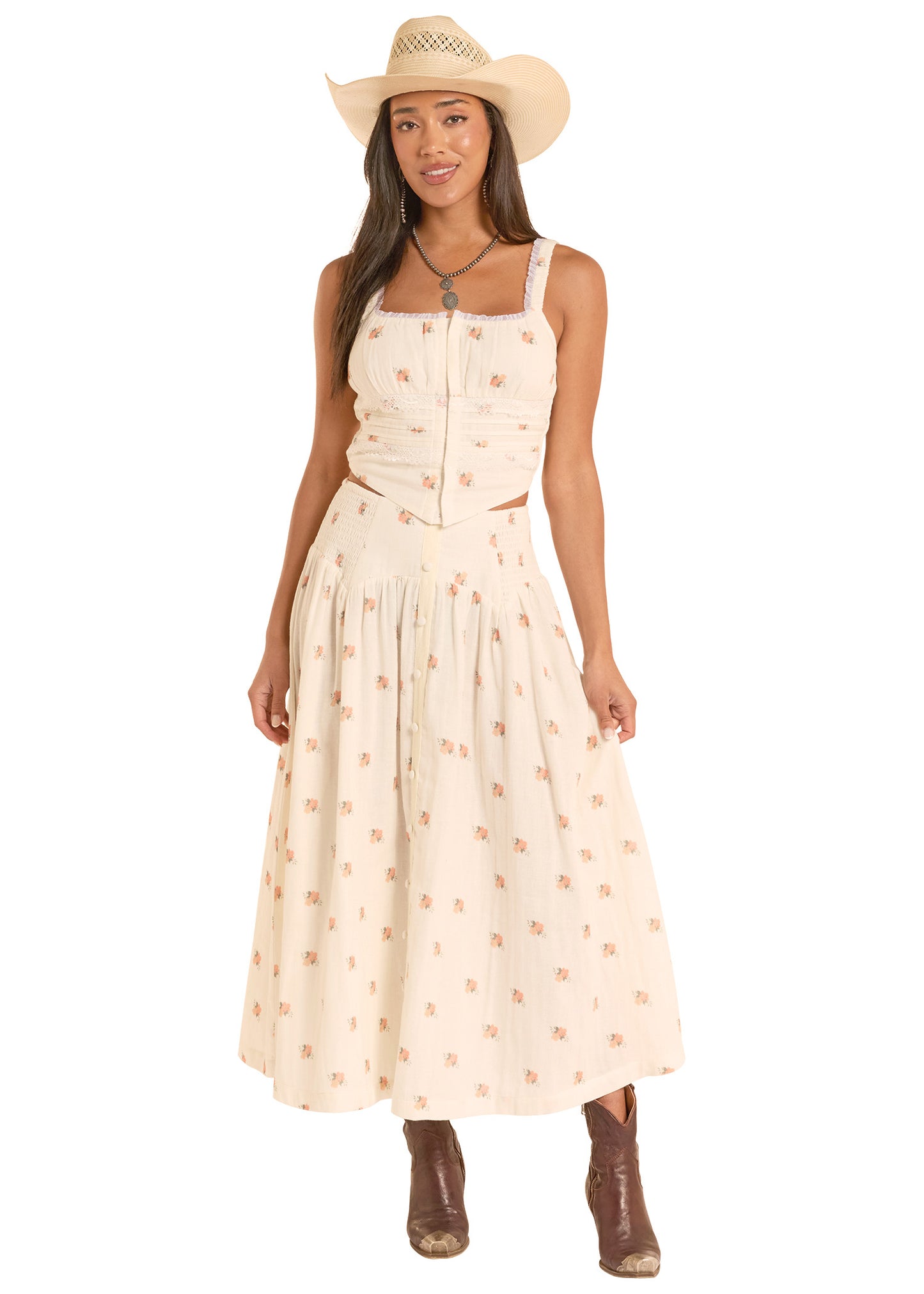 Woman wearing a beige dress with a subtle pattern, brown boots, and a straw hat on a white background
