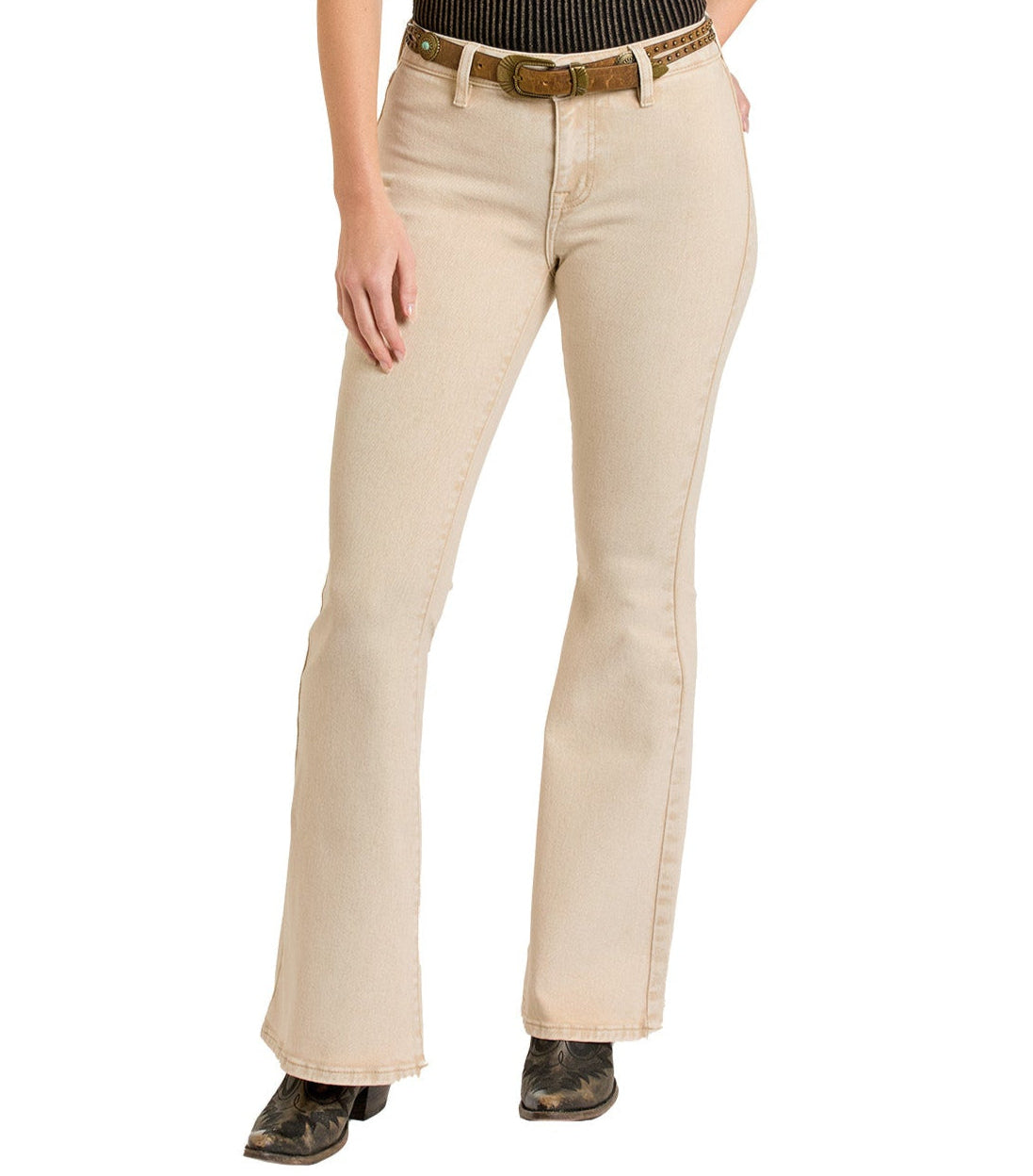 A person wearing Rock & Roll Denim's Tan Button Flare Jeans, a brown belt, and black boots stands with one hand on their thigh. Upper body is not fully visible.
