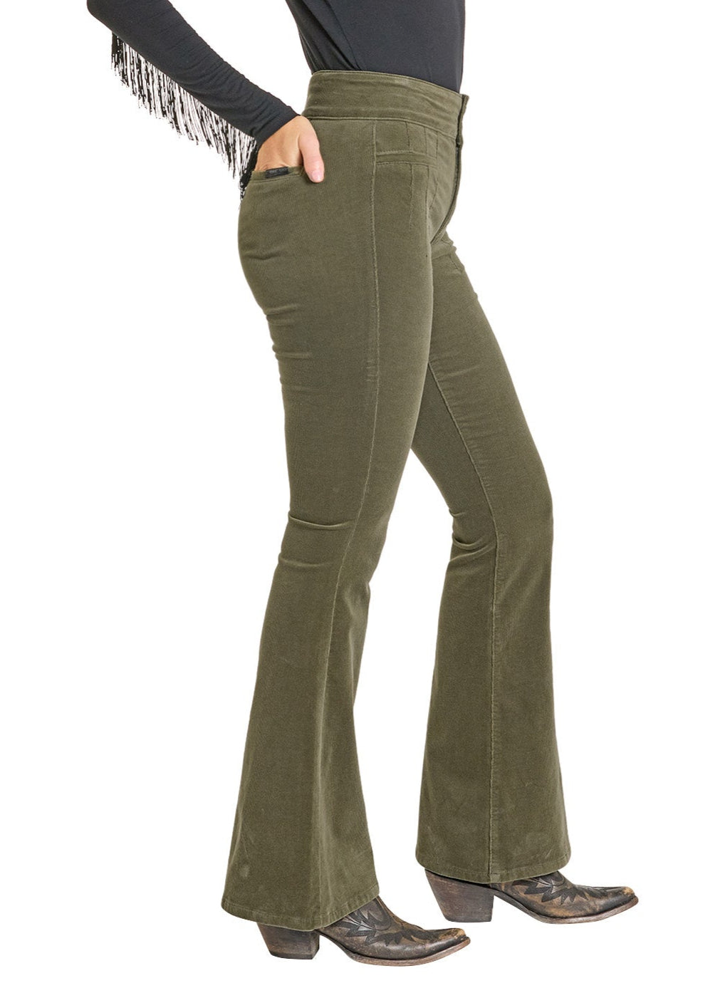 A person models Rock & Roll Denim High Rise Jade Corduroy Button Flare Pants with a black long-sleeve fringe top and black pointed-toe heeled boots, posing with one hand in a pocket against a white background.