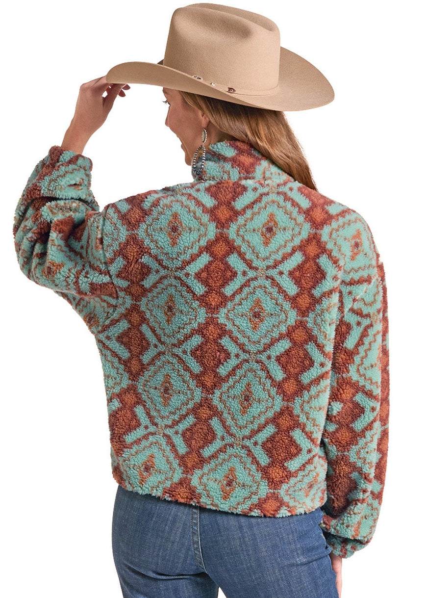 A woman shown from the back wearing a sherpa fleece pullover with a southwestern geometric pattern in turquoise and rust orange, paired with a tan cowboy hat and blue jeans, against a white background.