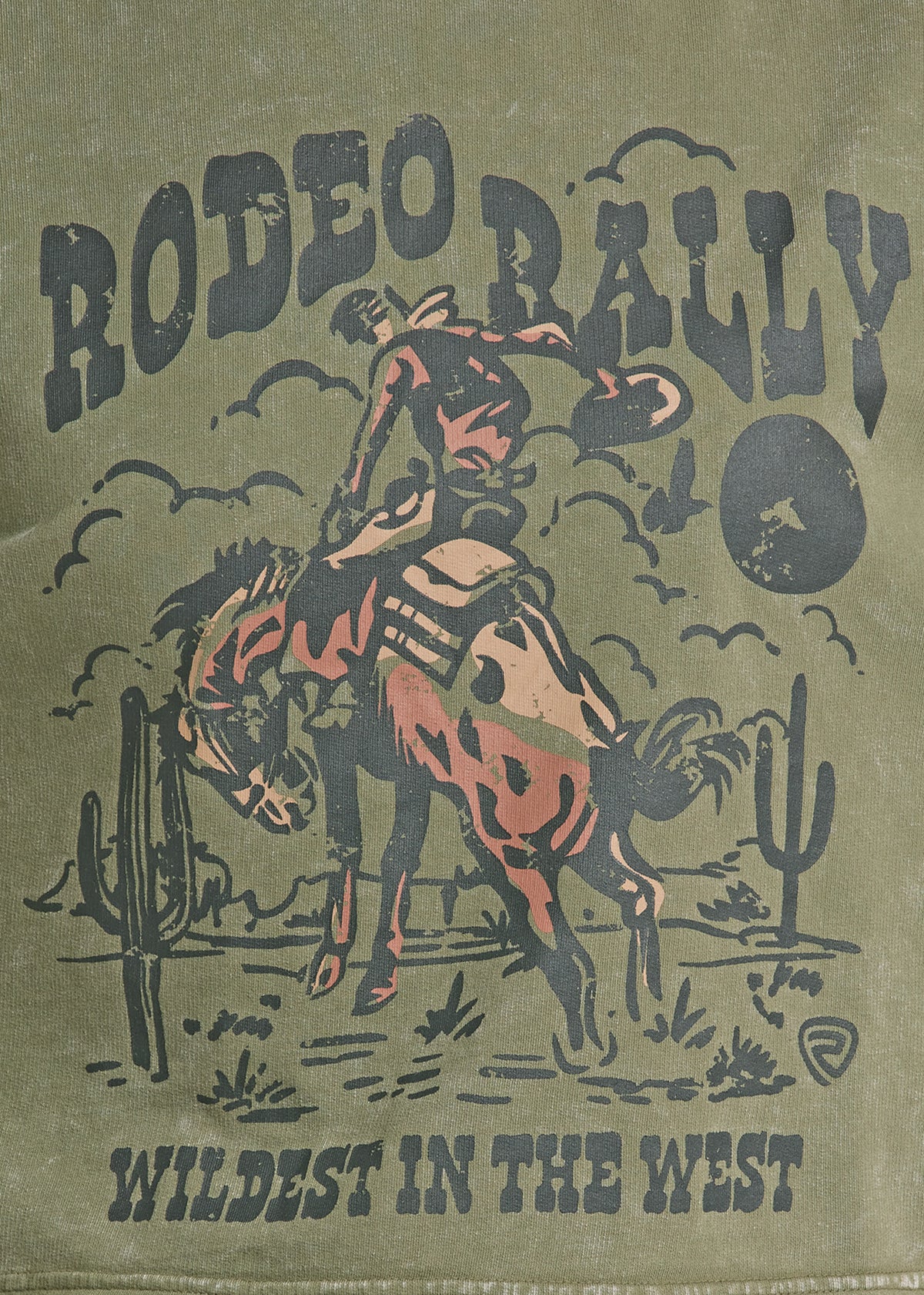 Vintage-style printed graphic on a distressed olive-green fabric background, featuring the words 'RODEO RALLY' and 'WILDEST IN THE WEST' with an illustration of a cowboy riding a bucking horse, cacti, and a moon.