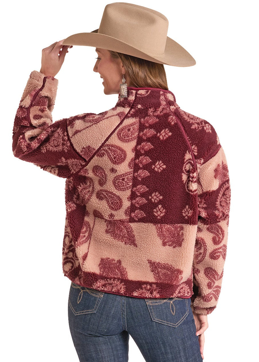 A woman shown from the back wearing a patterned western-style fleece jacket, blue jeans, and a tan cowboy hat against a plain white background.