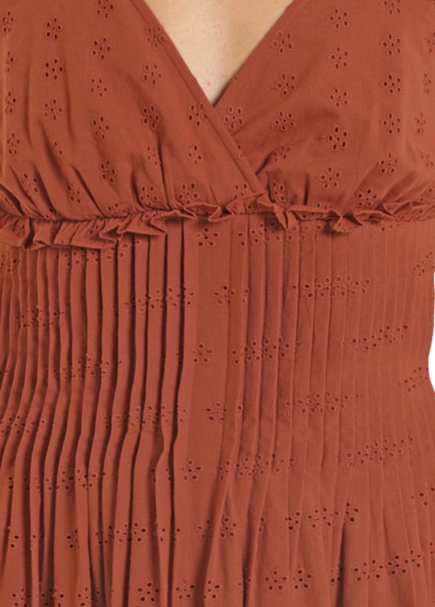 Close-up of a rust-colored dress with floral eyelet pattern