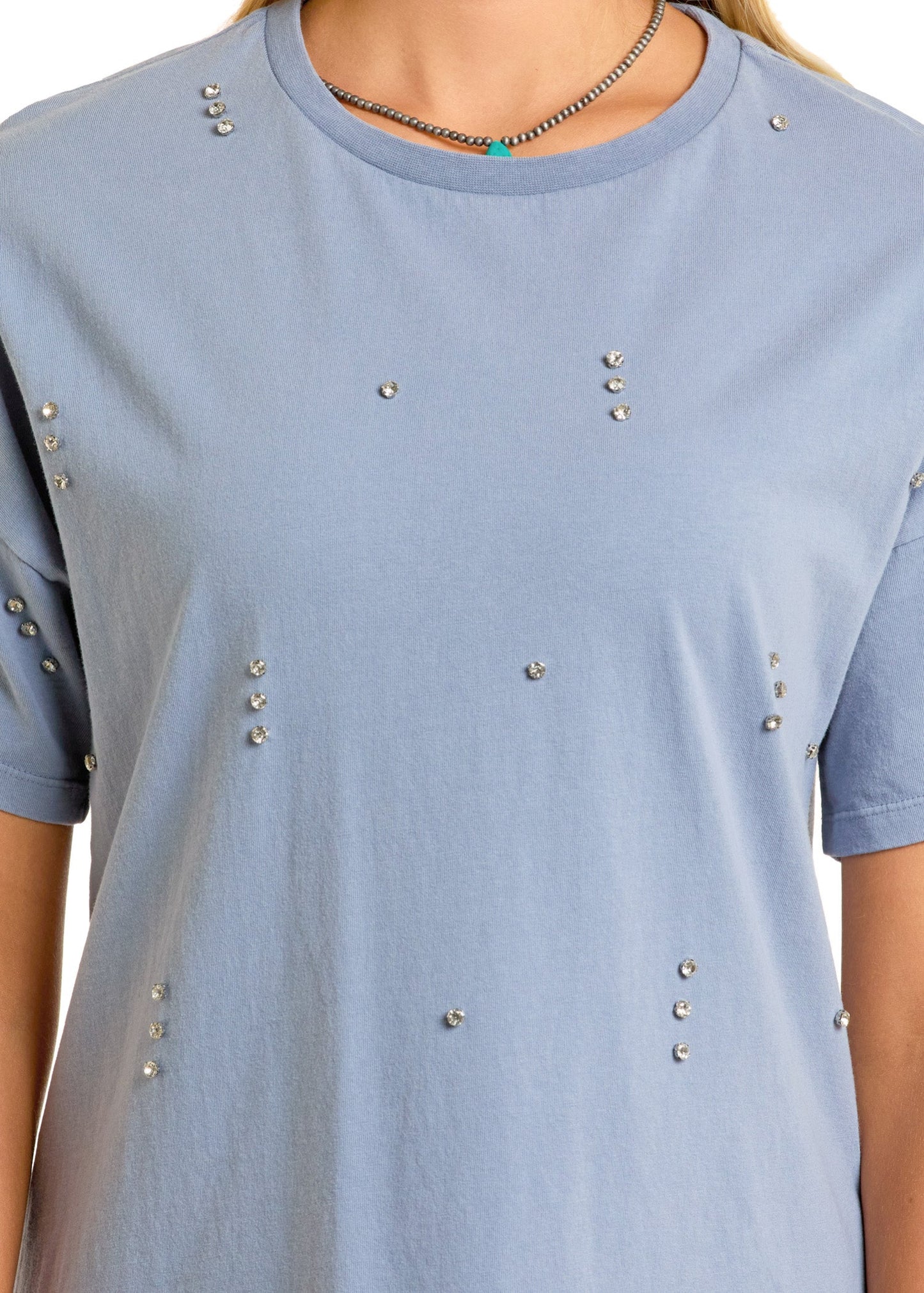 A person wearing the Rock & Roll Denim Rhinestone T-Shirt Dress; their face is not visible. They also have on a silver necklace with a small turquoise pendant.