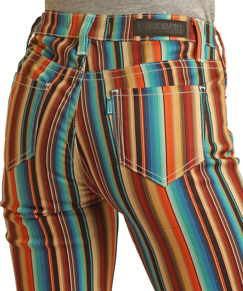 Close-up of a person wearing Rock & Roll Denim’s Hooey Striped High Rise Trouser Jeans, featuring colorful vertical stripes and a visible pocket with the brand label, highlighting western style.