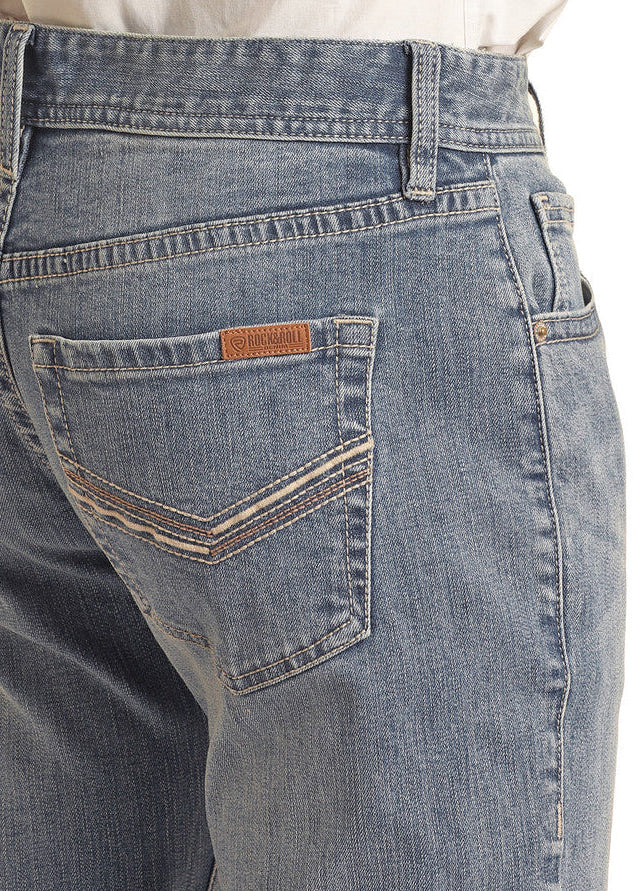 A person is shown from the back and waist down, wearing light blue Rock & Roll Denim Vintage '46 Regular Fit V Embroidered Stackable Bootcut Jeans with decorative back pocket stitching and a tucked-in white shirt.