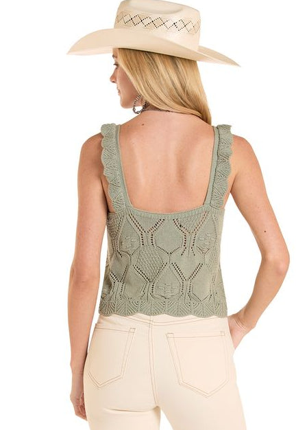 Woman wearing a green sleeveless top and beige pants on a white background