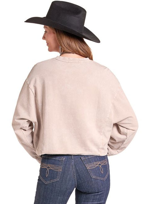 A woman shown from the back wearing a light beige long-sleeve cropped sweatshirt, dark blue jeans.